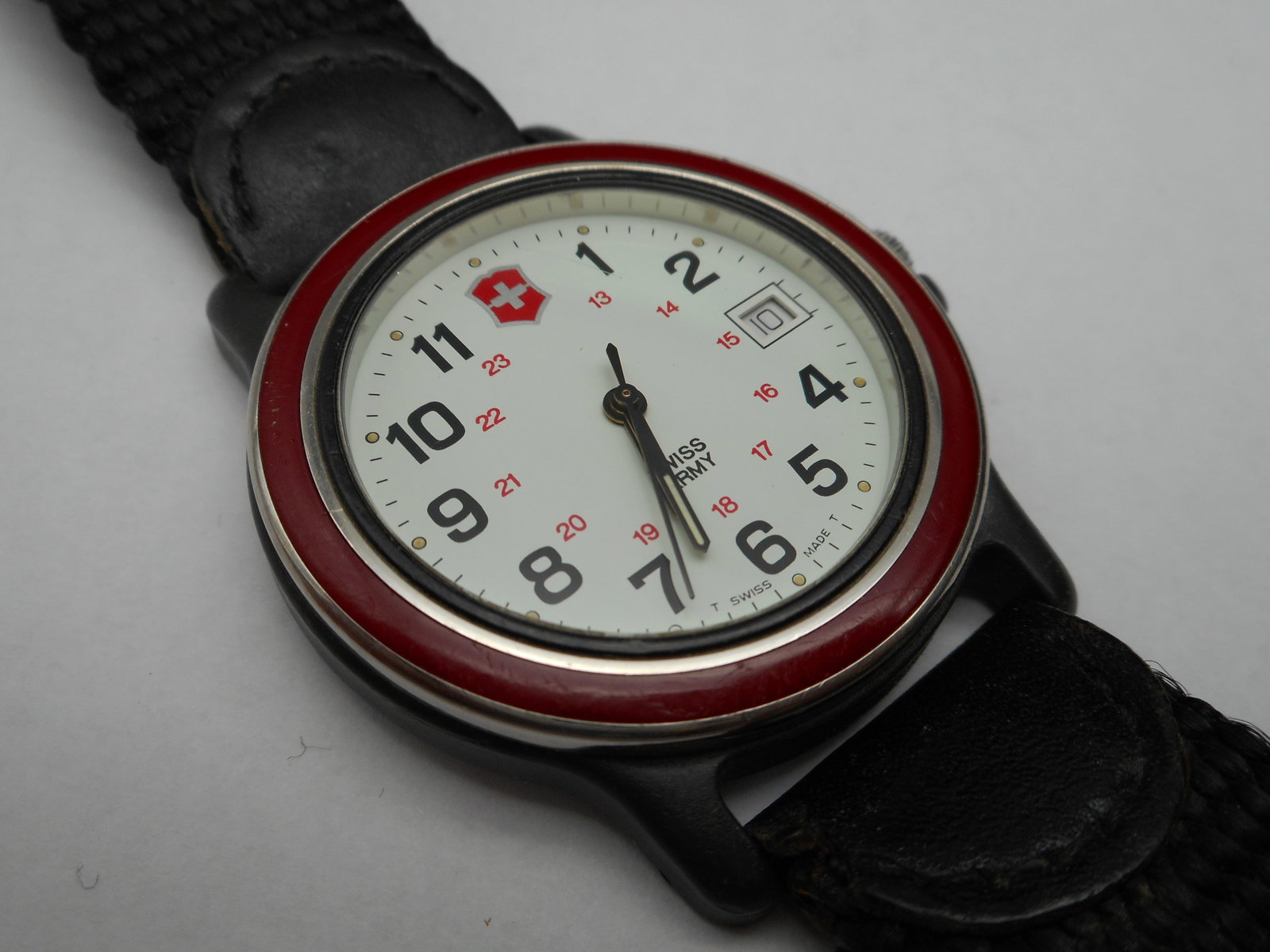 Vintage Swiss Army Quartz Men's Watch, Red Bezel, Analog, Date, Nylon Band, Needs Battery: Band shows wear from use Bidding on this item will be indication that the Bidder acknowledges that they have read and agreed to the Terms and Conditions posted to this Auction