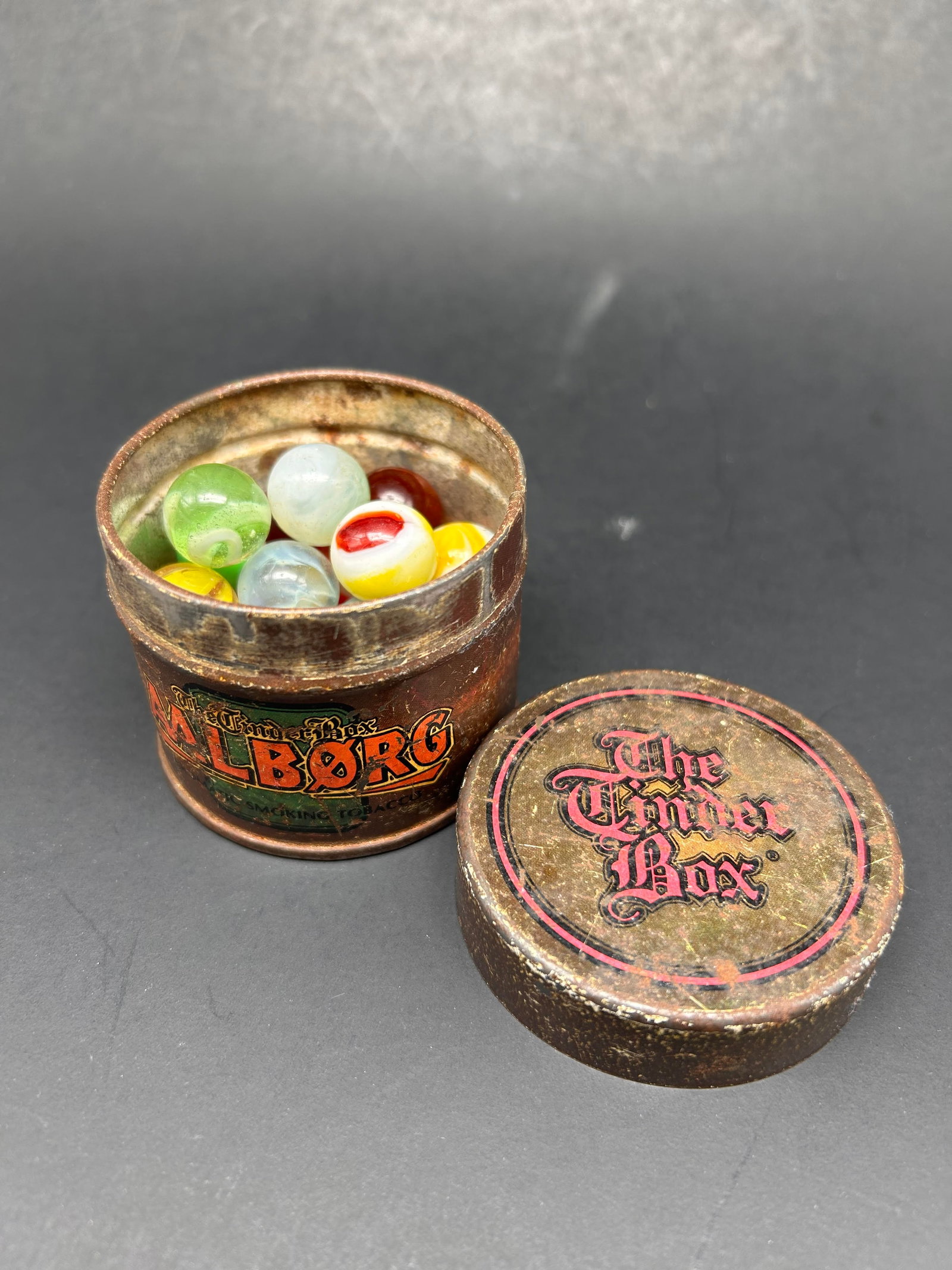 Antique Glass Marbles stored in AALBORG The Tinder Box Round Tin, 2.5" x 2" canister: Bidding on this item will be indication that the Bidder acknowledges that they have read and agreed to the Terms and Conditions posted to this Auction
