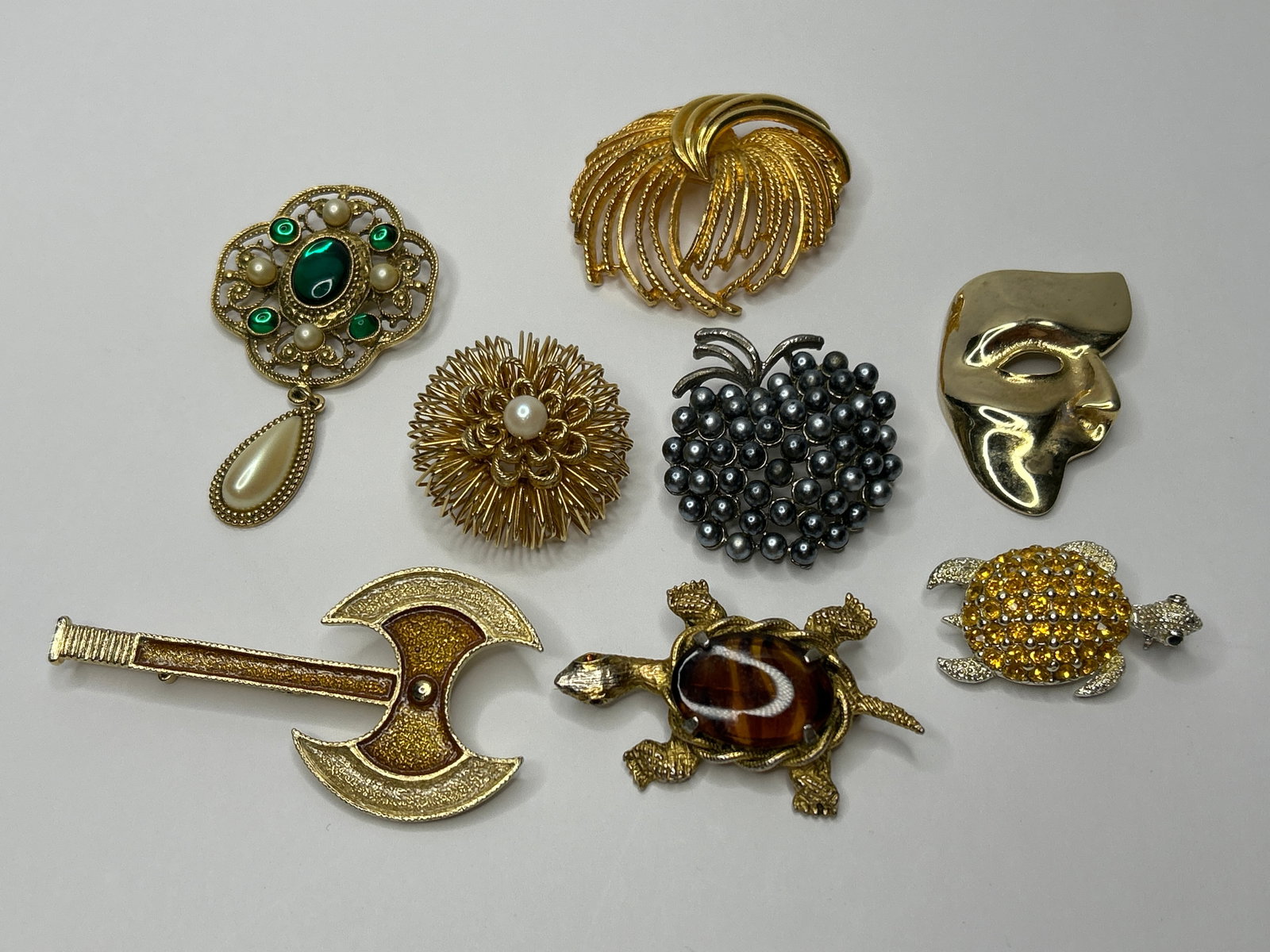 Collection of Unique Brooches, Mostly Gold Toned w/Assorted Stones, Enamel, Rhinestones, Faux Pearls: Largest Brooch is 3" long Bidding on this item will be indication that the Bidder acknowledges that they have read and agreed to the Terms and Conditions posted to this Auction