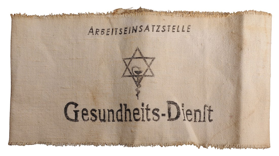 *German WWII Arbeitseinsatzstelle Jewish Labor Health Department Armband (A): A *German WWII Arbeitseinsatzstelle Jewish Labor Health Department Armband in good to very good condition. The armband has minor fading to the original designs and inscriptions with moderate staining 