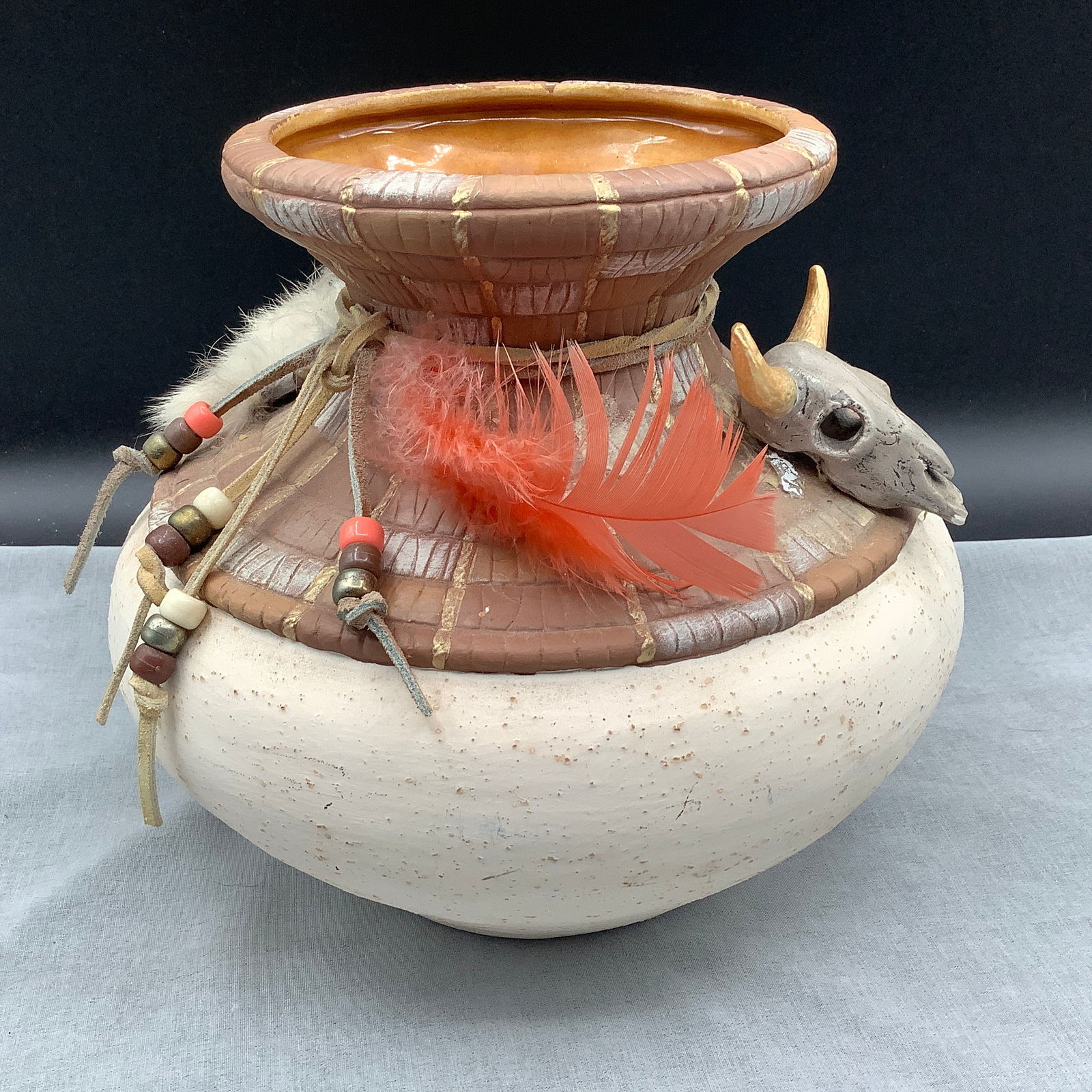 AZ Native American Signed Pottery with Applied Beaded Leather and Feathers with Mini Faux Skull: Pottery signed T.J and has applied felt on underside Upon close inspection of photos, skull has break at tip of lower jaw