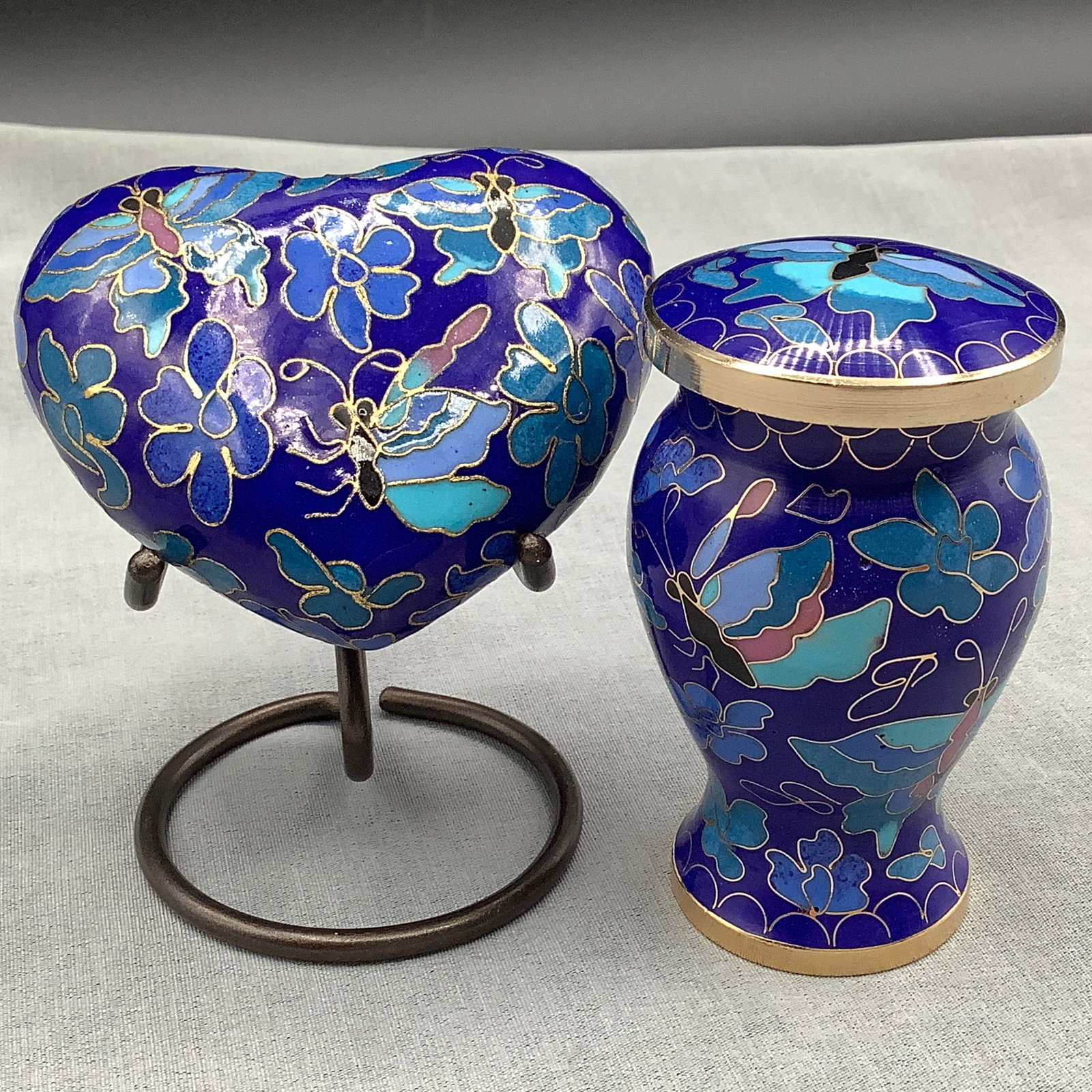 Pair of Small Cloisonne Trinket Boxes: Both blue tones with butterflies One heart shape with stand, one urn shape
