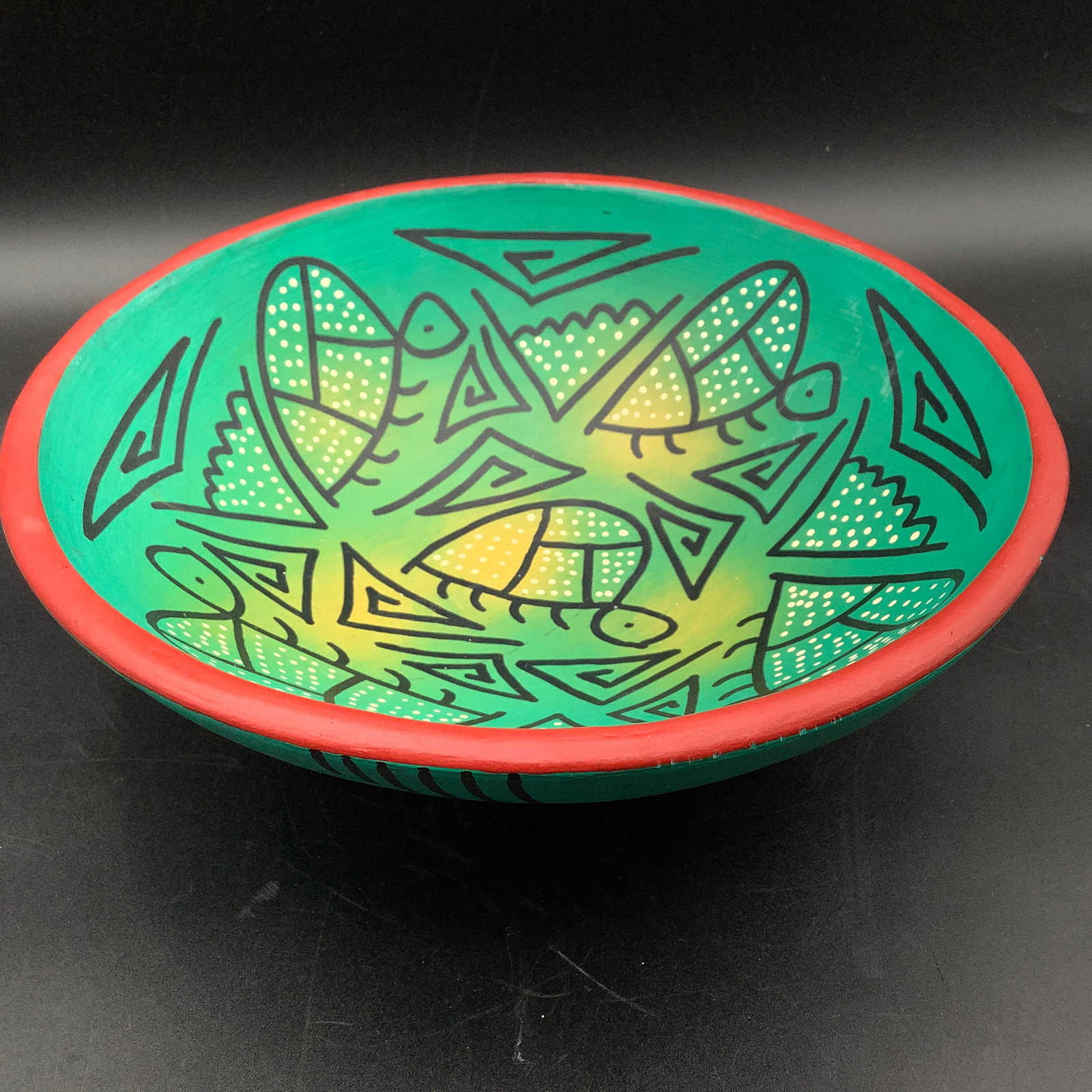 Hand Painted Pottery Bowl with Turtle Design: Unglazed, bisque pottery Green with yellow tinting, black simple shapes and turtles Red rim, black accents around exterior