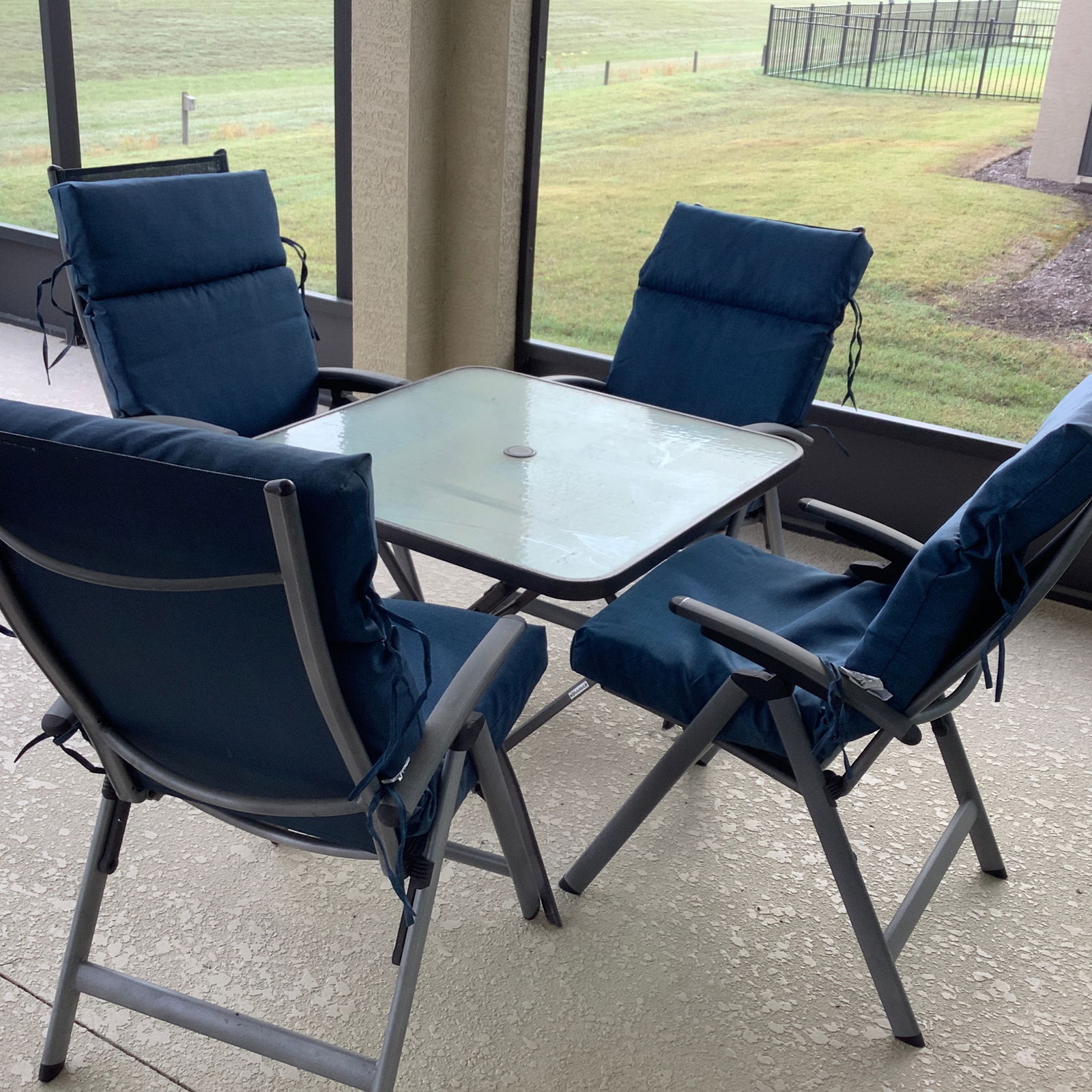 Patio/Lanai Table, 4 Chairs and Navy Blue Cushions: 34 inch glass top table. All chairs adjustable as well.