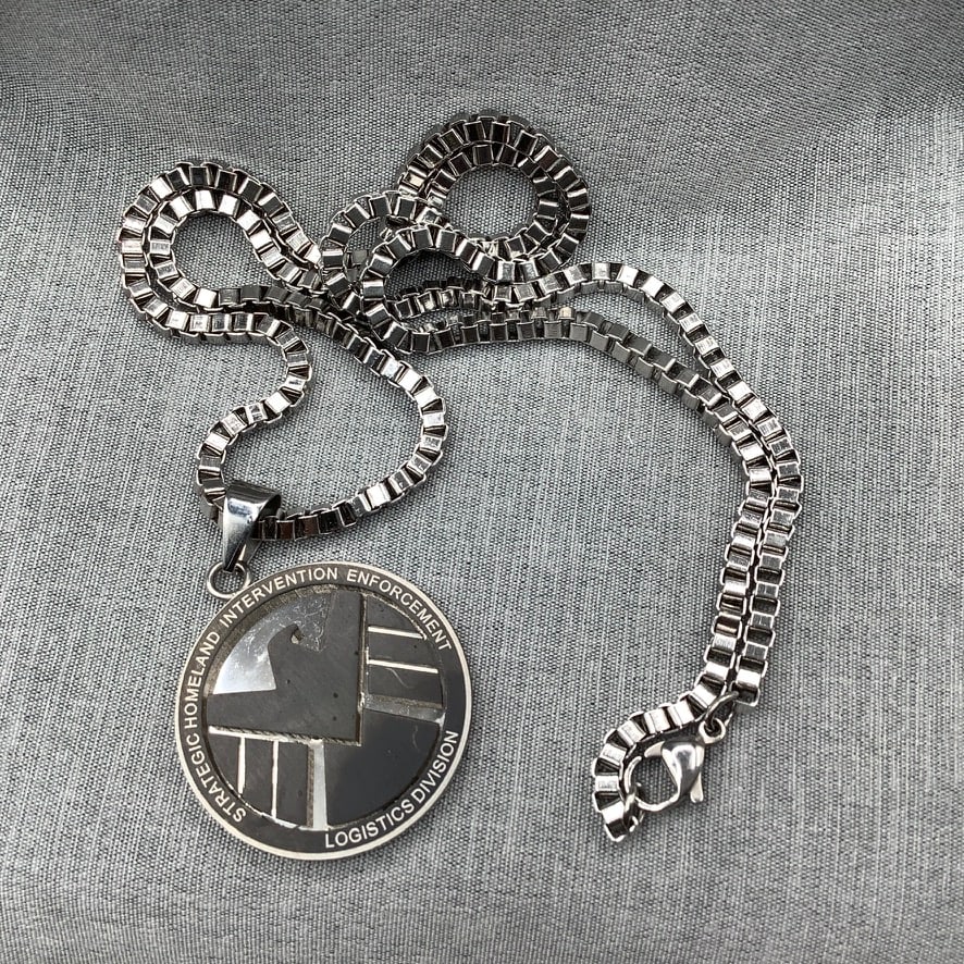 Marvel Stainless Steel Pendant on Box Chain Necklace: Pendant has mirror finish behind blackened eagle symbol Perimeter "Strategic Homeland Intervention Enforcement Logistics Division" Chain is 23 inches with pendant 1.5 inch with bale