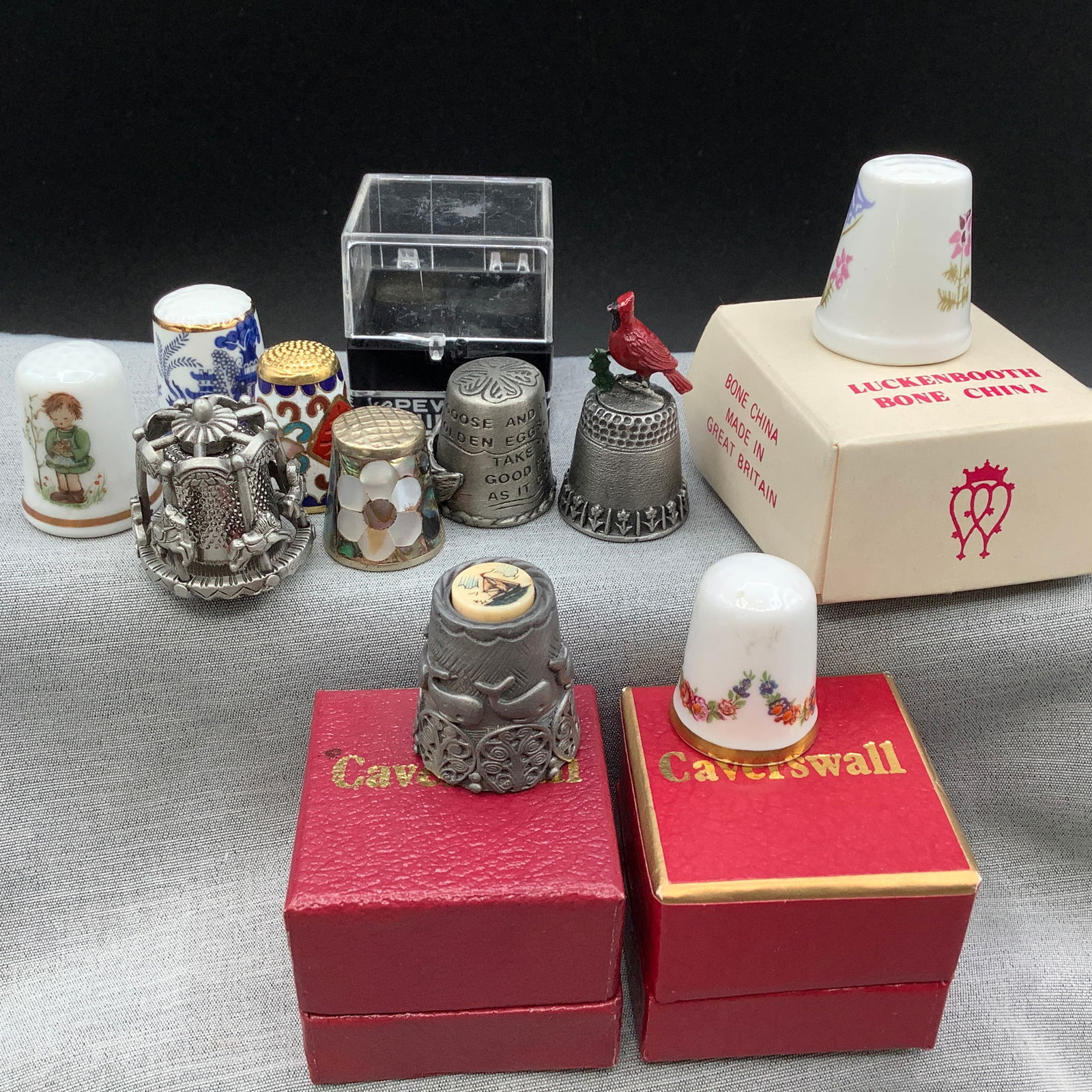 10 Thimbles: Pewter, Caverswall, Cloisonne, Mother of Pearl: Caverswall Pewter Nautical with porcelain top, Caverswall Porcelain, Luckenbooth Great Britain Bone China, Pewter with cardinal, Pewter dual layered with floating carousel horses, Golden Goose that sl