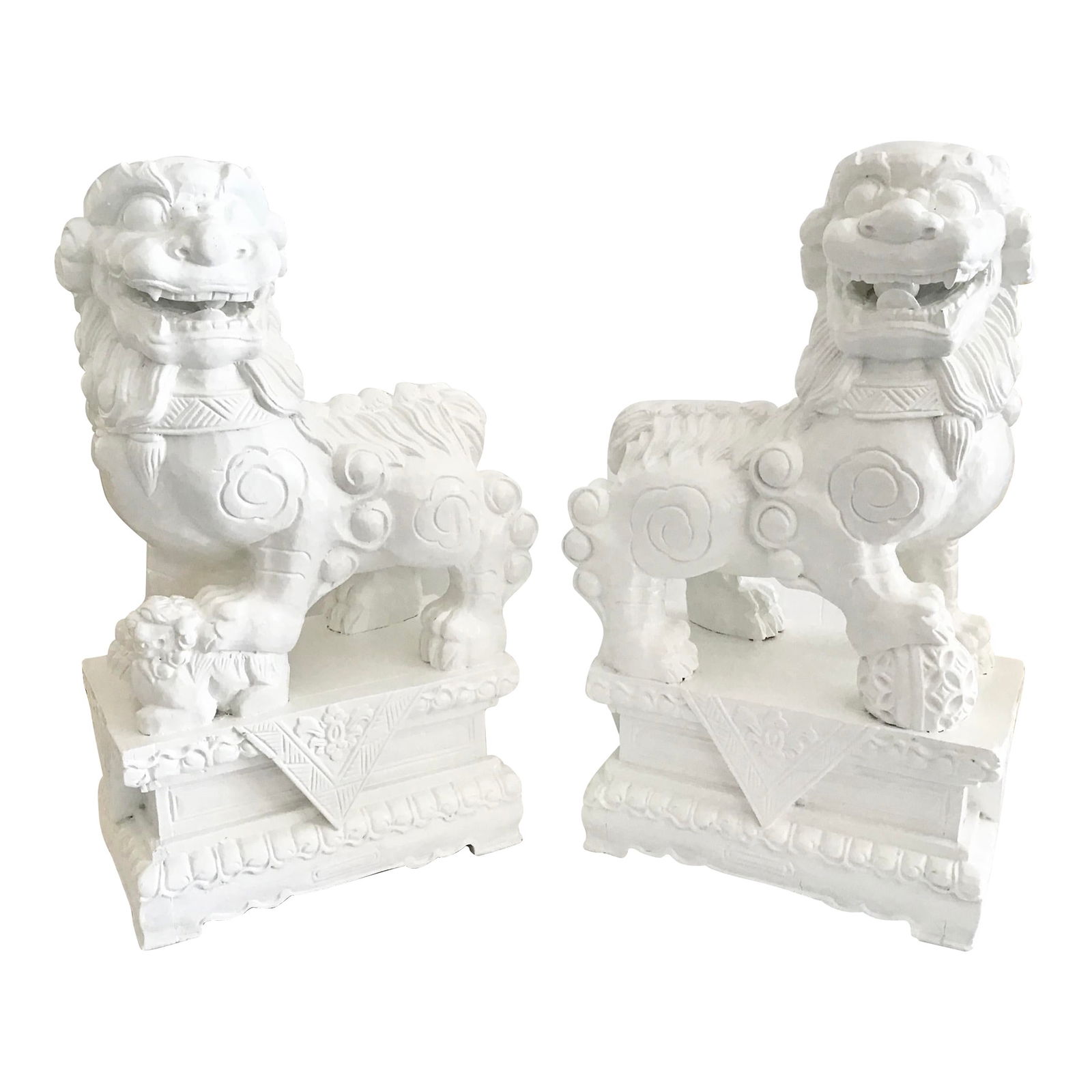 White Foo Dogs Carved in Wood Base Floral Figures, a Pair: 11.5"W × 6.25"D × 19.5"H Early 20th Century pair of freshly lacquered in white fantastic large foo dogs made with wood. The floral carving details at the base is amazing. Add it to your collection o