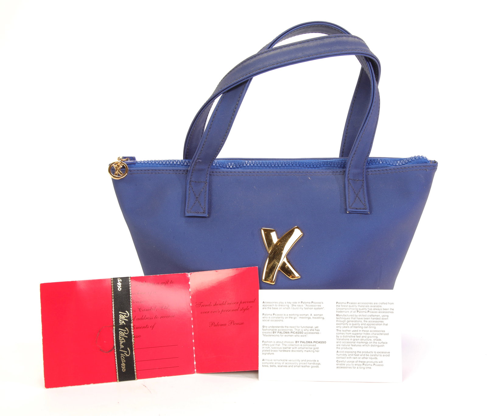 PALOMA PICASSO Designer Handbag W/ Paperwork: A bright blue fabric Paloma Picasso designer handbag with original paperwork. Gently used condition. Dimensions:H: 7" x L: 11.5" x W: 4" Strap Drop: 3-4"