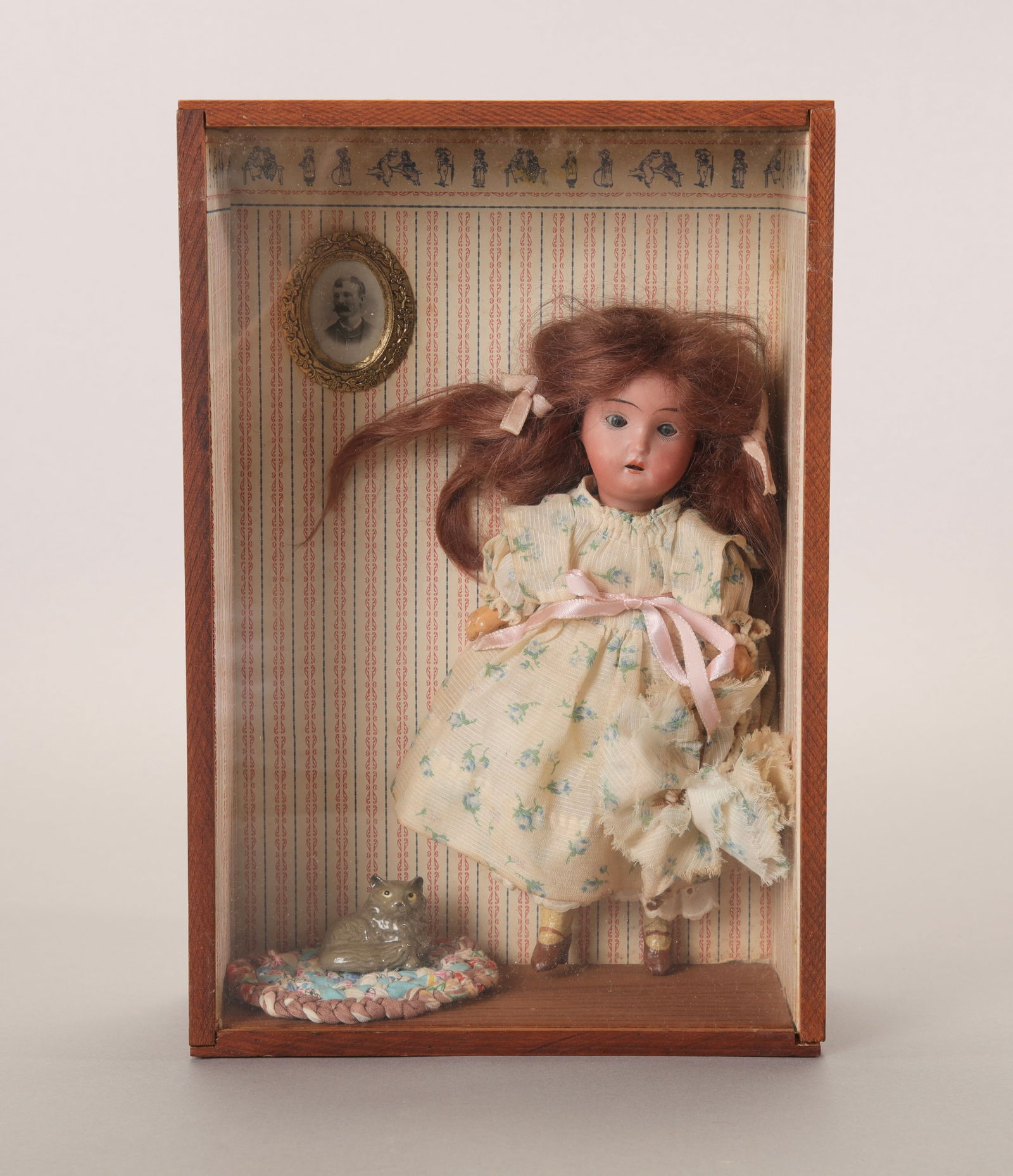 ANTIQUE 8.5" BISQUE DOLL FRAMED IN SHADOWBOX: An antique bisque doll framed in a shadowbox. Marked on back of box "1900 bisque head with paper machier body and limbs."Shadowbox measures: 12" x 8" x 3.5" Doll measures about 8.5" tall. Doll has red