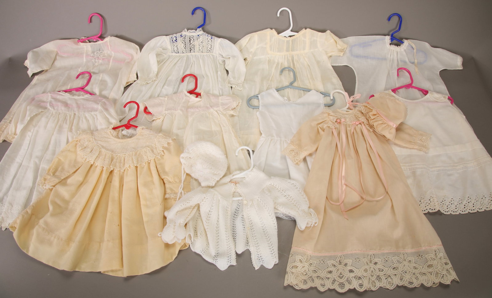 11 ANTIQUE & VTG DOLL / BABY DRESSES, SWEATER, CAP: A lot of 10 antique and vintage doll or baby dress and a little crocheted sweater and matching cap.
