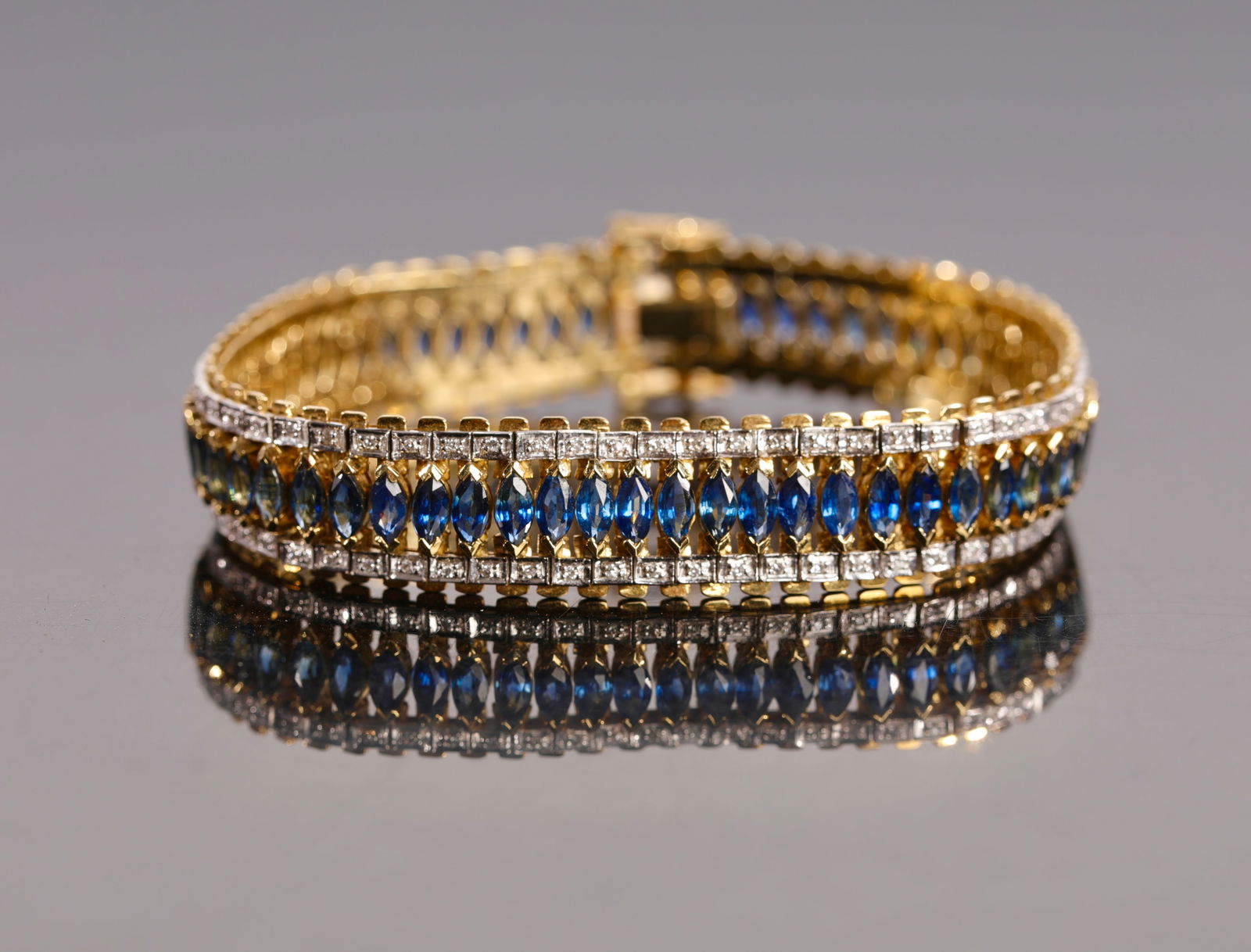 DAVID YURMAN SAPPHIRE, DIAMOND, 18K GOLD TENNIS BRACELET: An exquisite David Yurman tennis bracelet comprised of sapphires and diamonds and set in 18k yellow gold. Features two safety clasps on either side. Tested for gold purity and gemstone authenticated.