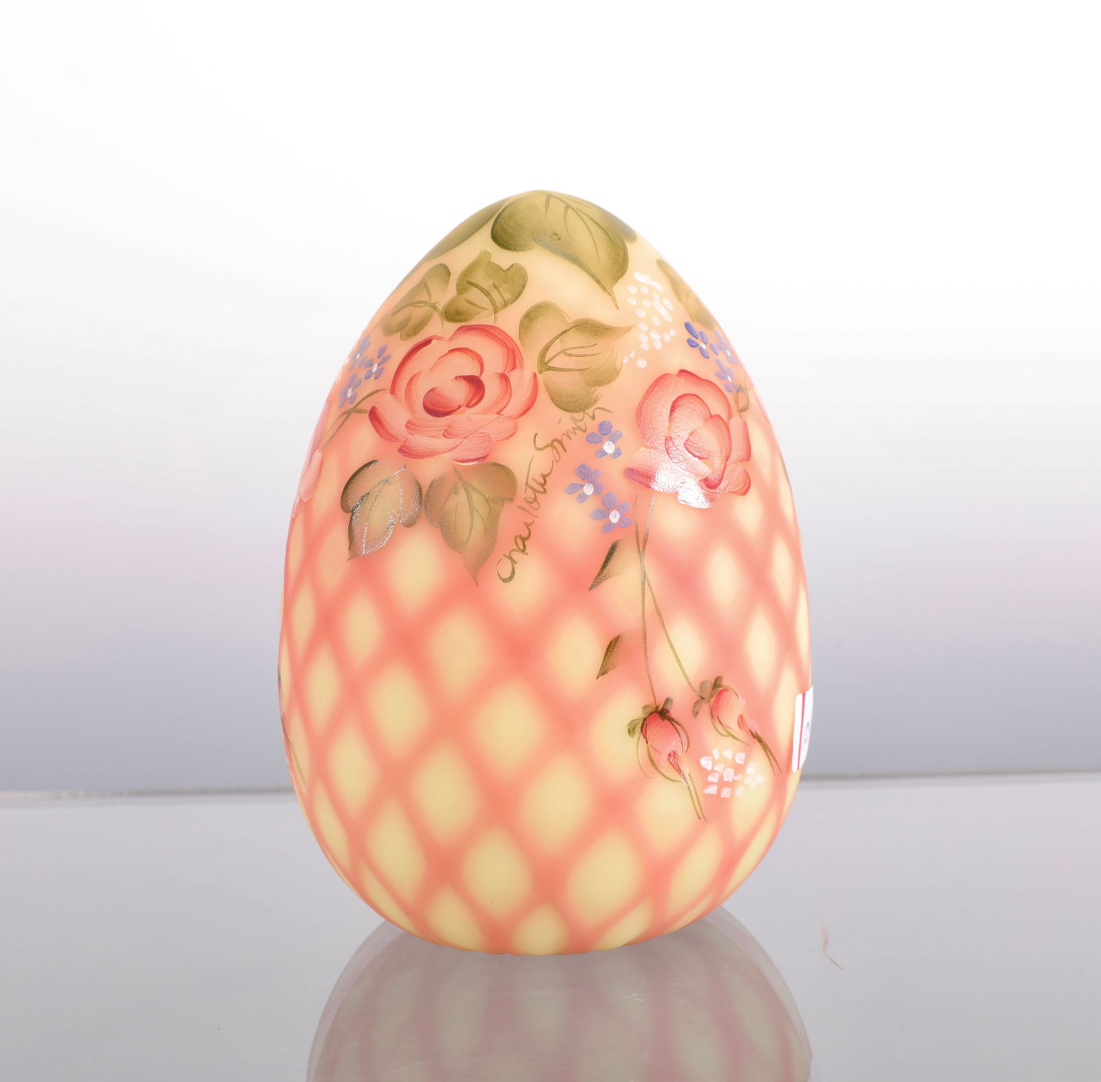 FENTON BURMESE HAND-PAINTED GLASS EGG UV REACTIVE: A lovely Fenton Burmese glass egg with diamond optic and hand painted floral design. Signed. UV reactive- glows under a black light. Measures: 5" H x 3.25" diam INV# - Red 104