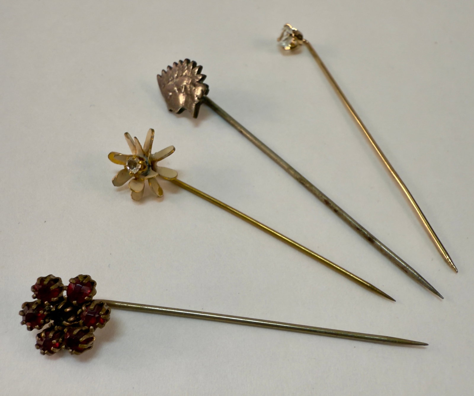 Group of Four Antique and Vintage Stick Pins: From an upstate, NY estate collection. Group of four antique and vintage stick pins including one cut from an Indian Head cent, a silver Victorian Garnet cluster, and two costume rhinestone pins.