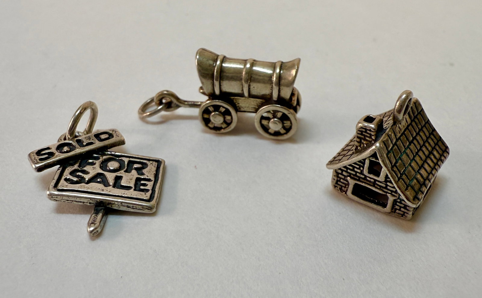 Group of Three Vintage Sterling Silver Charm Bracelet Charms - Wagon, For Sale Sign, House: From an upstate, NY estate collection. Group of three vintage sterling silver charms including a covered wagon, for sale sign, and a house. Sign and wagon both marked sterling and with maker's marks, 