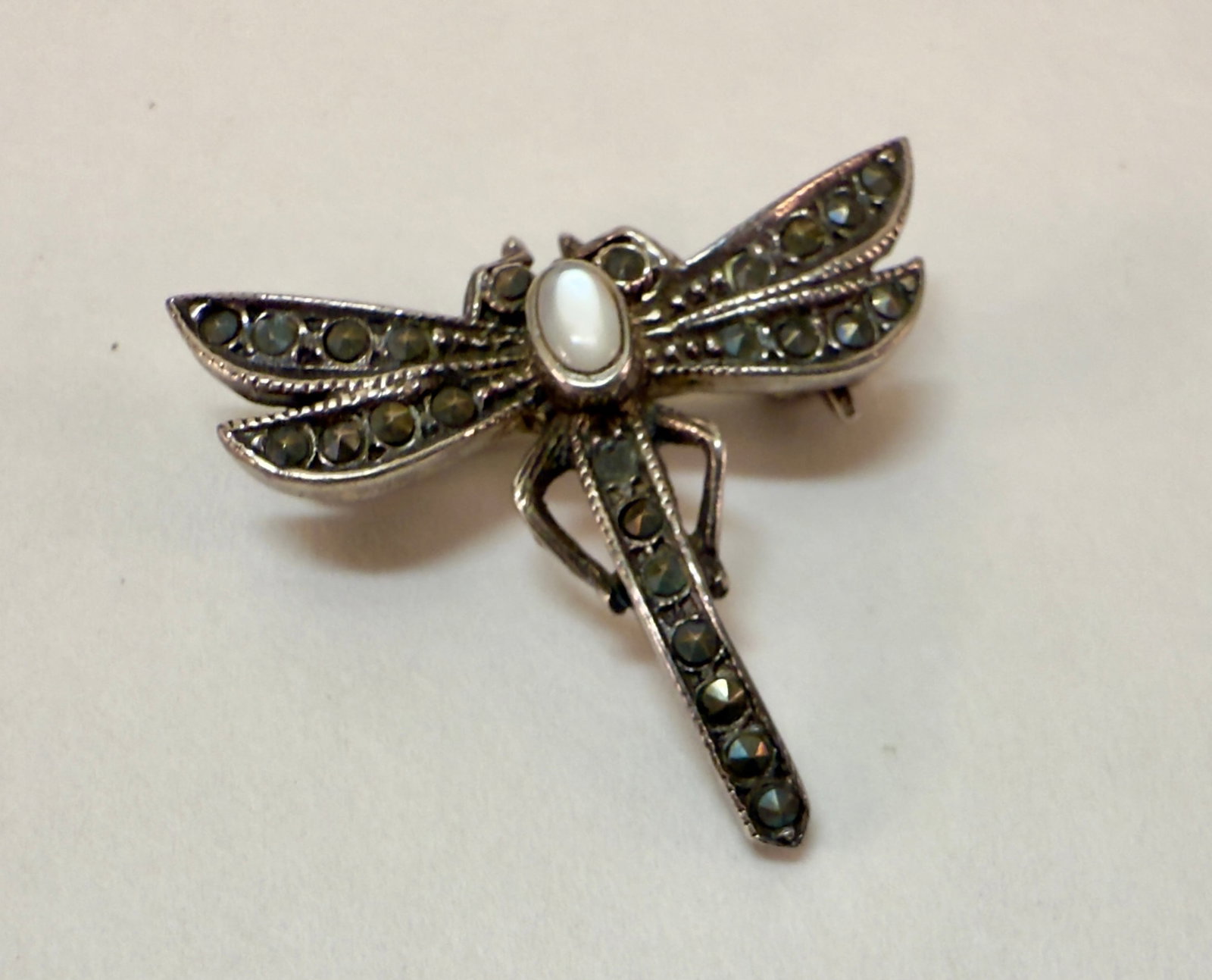 Sterling Silver Dragonfly Pin Moonstone Marcasite: From an upstate, NY estate collection. Delicate vintage sterling silver dragonfly with moonstine cabuchon at head and cut marcasite stones aloing boday and wings. Marked 925 on back of tail. Barrel cl