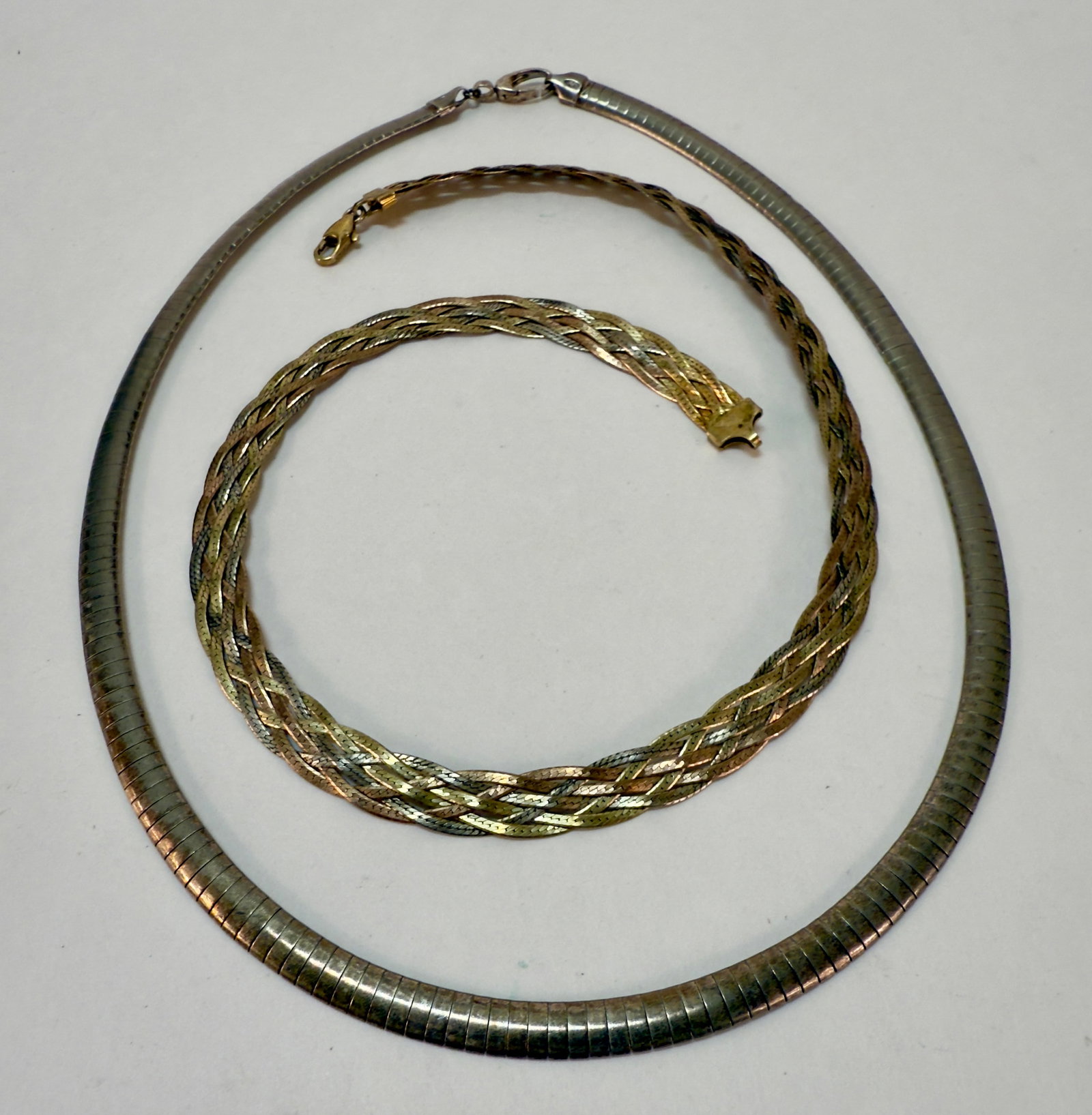 Pair of Sterling Silver Vintage Chain Necklaces: From an upstate, NY estate. Pair of marked and tested sterling silver necklaces, one tri-tone gold plate herringbone braid (marked 925 Italy) and the other snake chain marked 925. Braided measures app