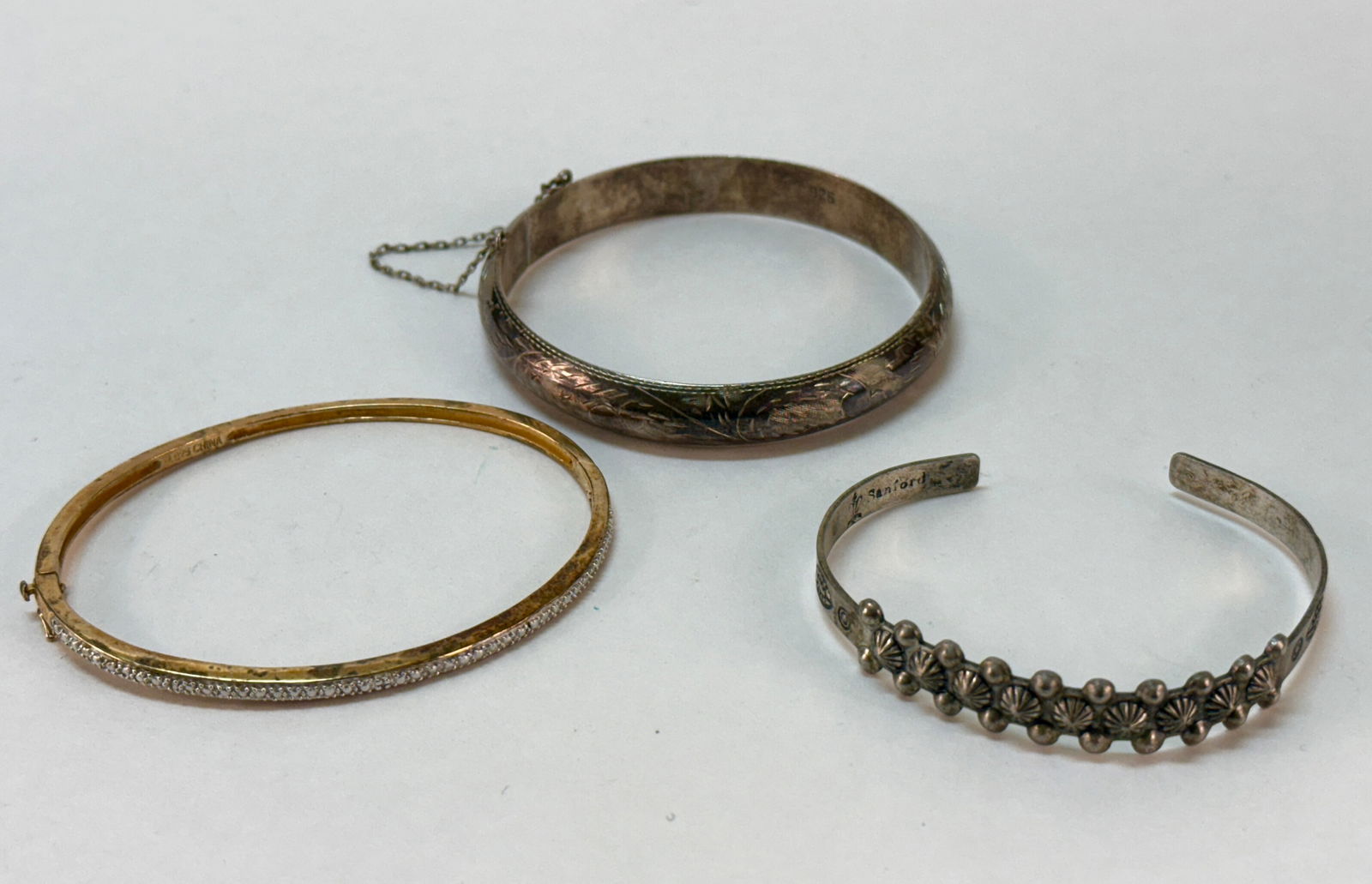 Group of Three Vintage Sterling Silver Bracelets: From an upstate, NY estate. Group of three sterling silver bracelets with various patterns and designs. Navajo old pawn style cuff, etched bracelet with safety chain and gold-plated CZ studded bangle