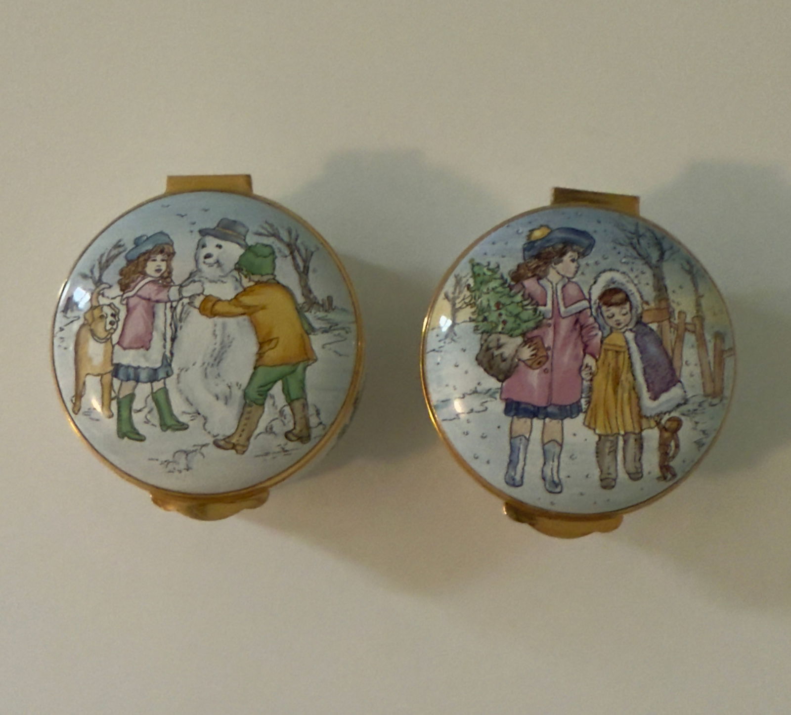 Pair of Harrod's Christmas Porcelain Pill Boxes Enamel Limited Edition Crumles & Co England: From an upstate, NY estate. Pair of limited edition Harrod's Christmas Boxes, made by Crumles & Co, England. Hand painted lids with Christmas scenes, in enamel. For years 1985 and 1986. Each measures