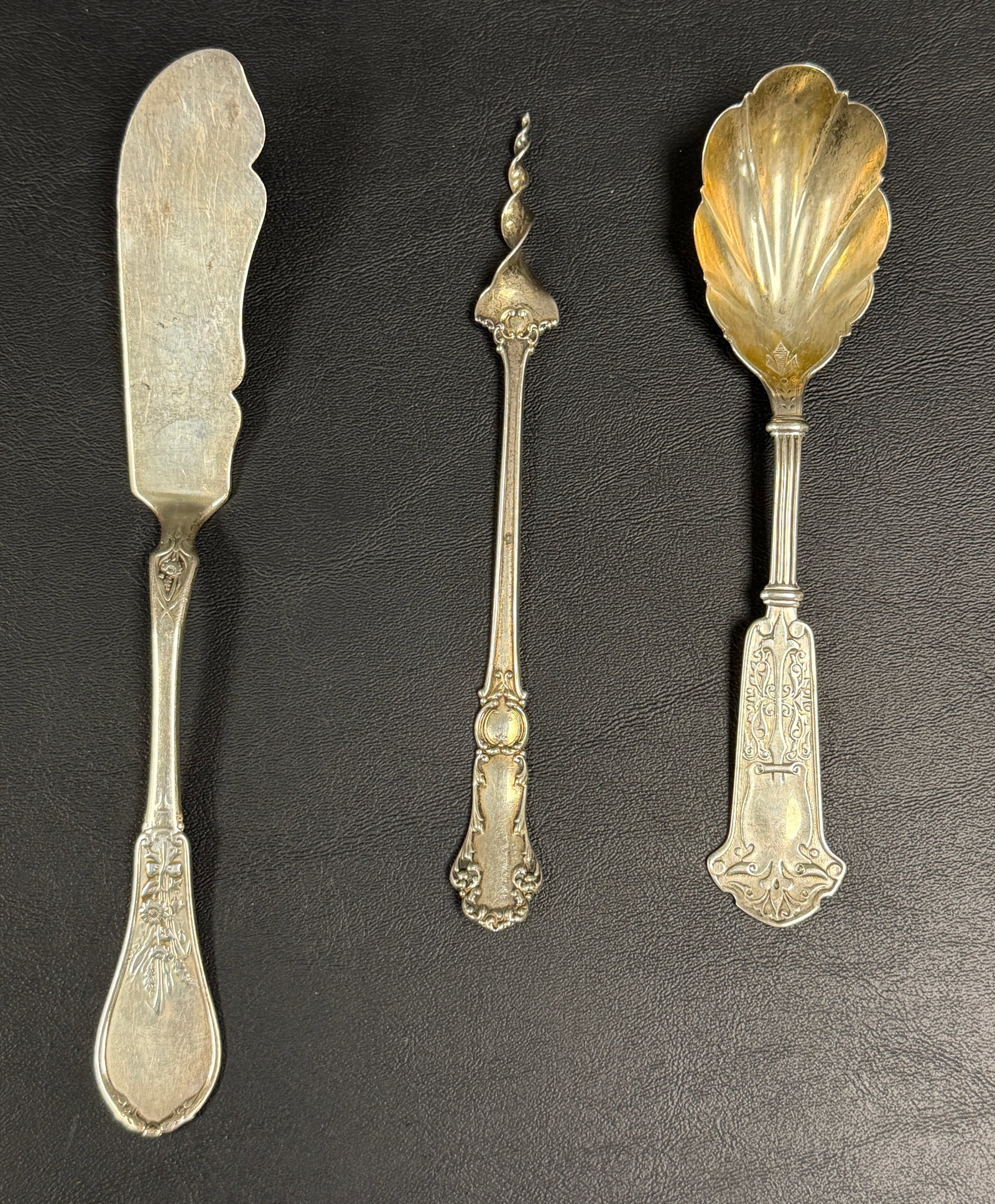 Group of 3 Ornate Sterling Silver Flatware Pieces: From an upstate, NY estate. Group of three antique sterling silver table pieces, including a butter pick made by Mechanics Sterling, Art Nouveau design sugar shell with European marks, and coin