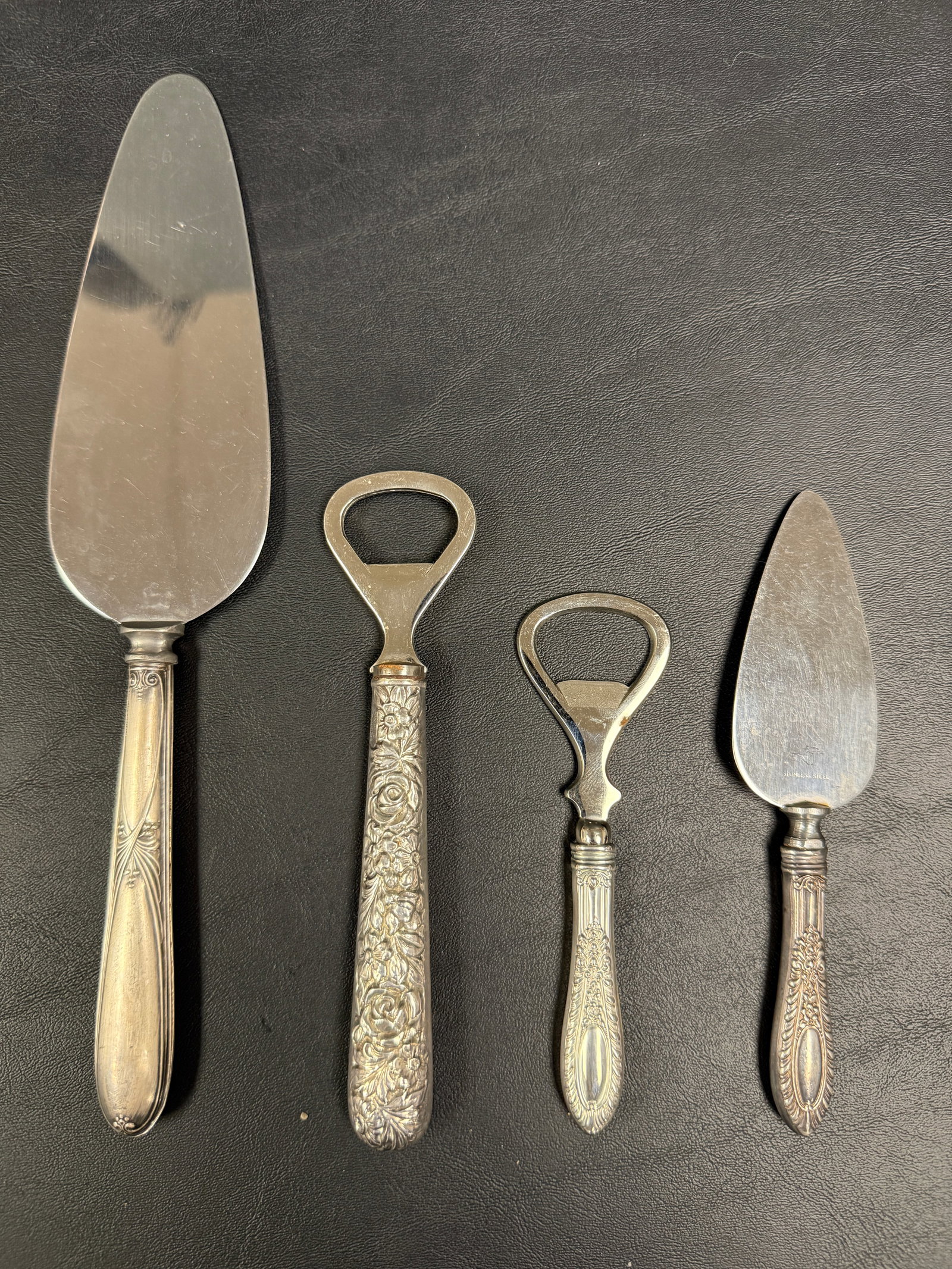 Group of 4 Sterling Silver Handle Repousse Bottle Openers Servers: From an upstate, NY estate. Group of four sterling silver handled bottle openers and servers. Each marked, makers unknown. Largest (cake server) measures approx 10.25". Group weighs approx 195 grams.