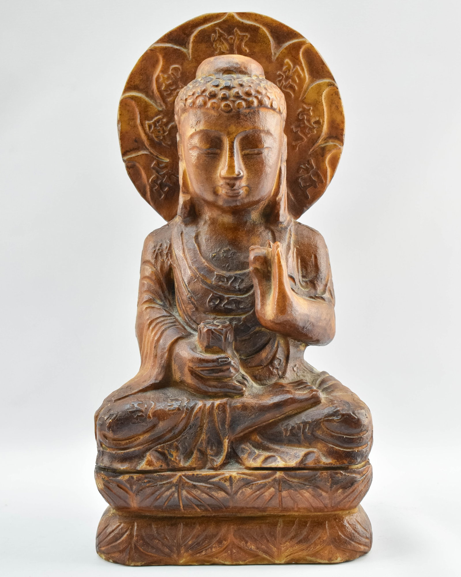 Carved Buddha Statue: Statuette of a seated Buddha figure meditating featuring characters in relief on the halo and underside. The statuette is heavy and appears to be made from a combination of stone and resin.
