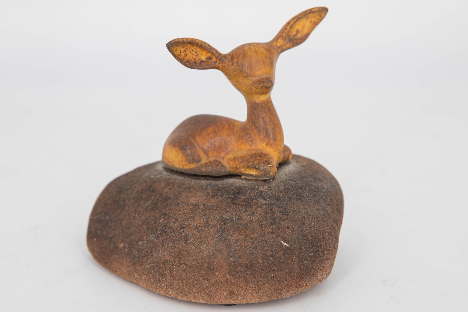 Maigon Daga, Ceramic Sculpture of Fawn on Stone: Ceramic sculpture of a deer fawn attached to a large stone, by artist Maigon Daga. Figure is glazed a mottled brown color. Signed Daga on bottom.
