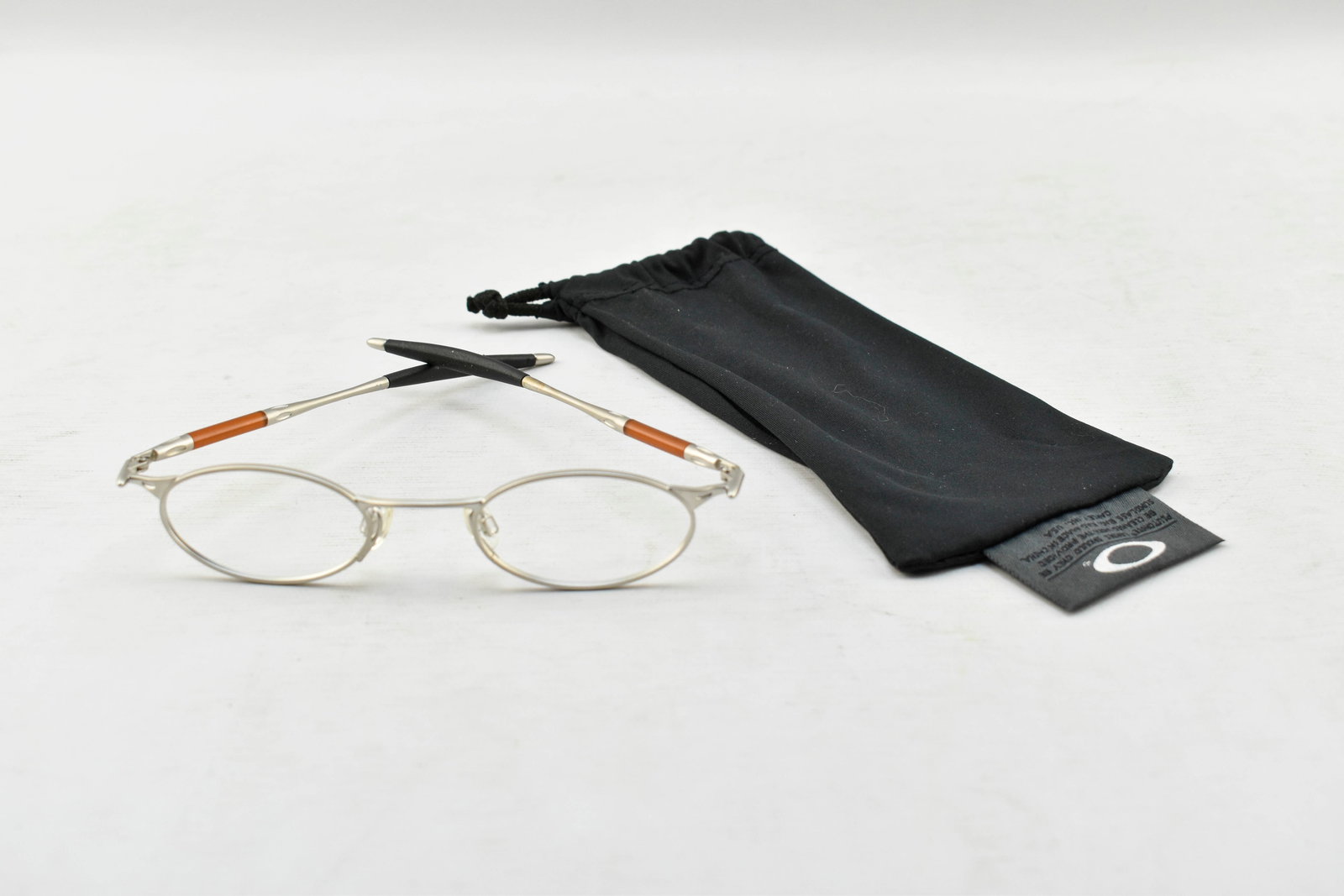 Oakley Jordan OO Wire Frame Eyeglasses, Silver/Brown/Black: Oakley Jordan OO wire frame eyeglasses with a silver body and brown and black details/ear pads on the temples. Without lenses. Numbered 46 22 inside nose bridge. Comes in soft case.