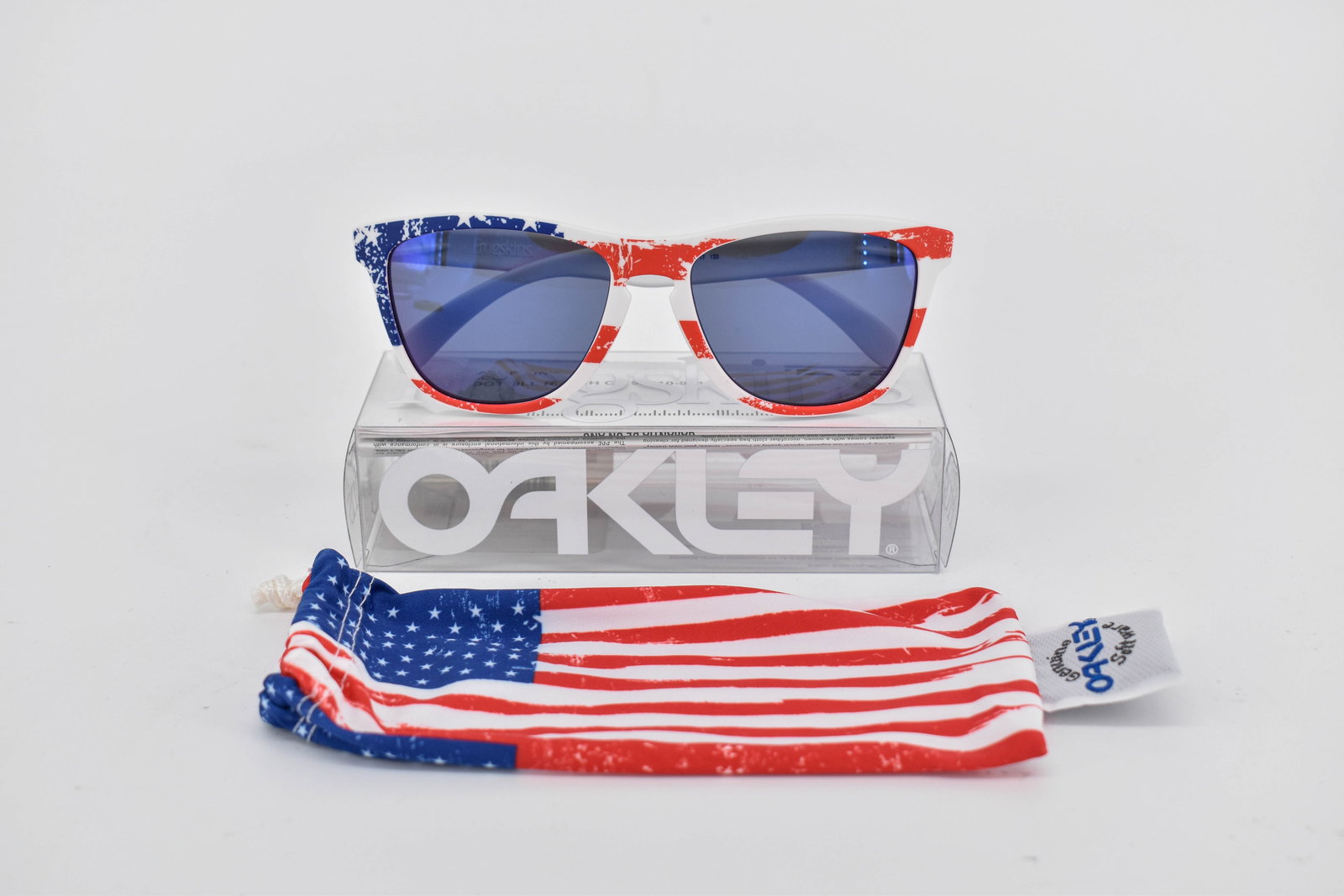 Oakley Old Glory Frogskin Sunglasses, American Flag/Red Iridium: Oakley Old Glory Frogskin sunglasses, with matte white frame printed with an American flag design and red iridium lenses. Model 24-318 55 17 133. In original box. Comes with soft case.