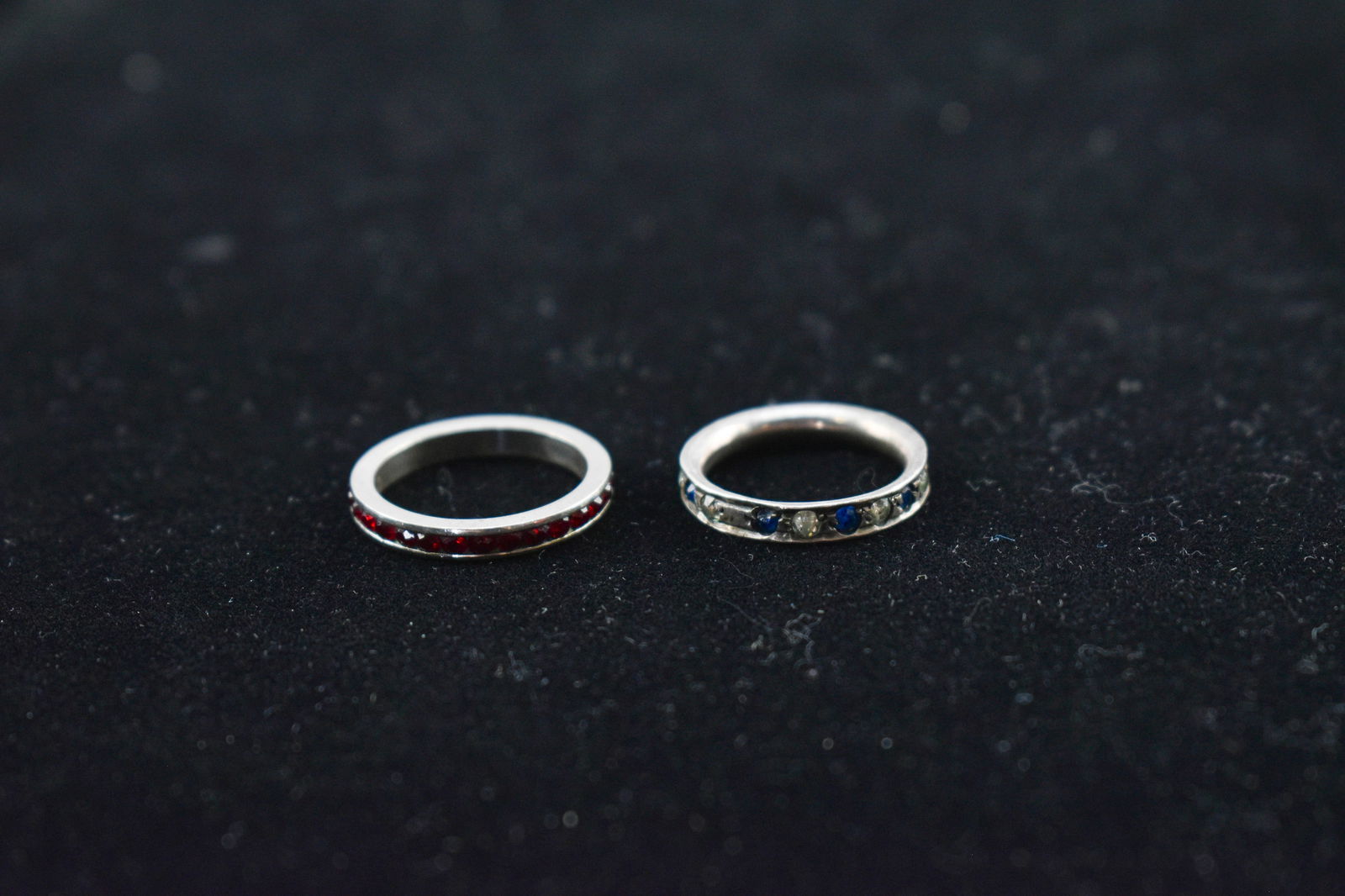 Vintage Inlaid Sterling Silver Rings: Two sterling silver stacking rings, one inlaid with red stones and one inlaid with cool tone stones. The red stones may be garnet but have not been tested. Both have approximately .75 inch diameters.
