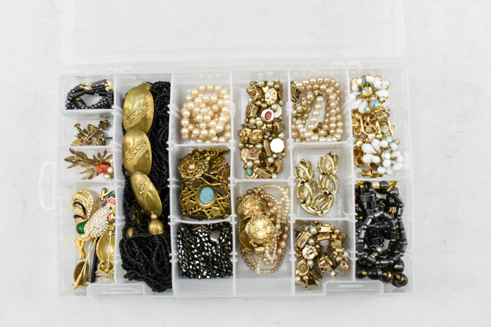Large Group of Gold-Tone Costume Jewelry: Group of vintage costume jewelry in a transparent ArtBin jewelry organizer including faux-pearl necklaces, chunky link bracelets, a rooster brooch marked 21370, an owl brooch marked A2361, a screw-top