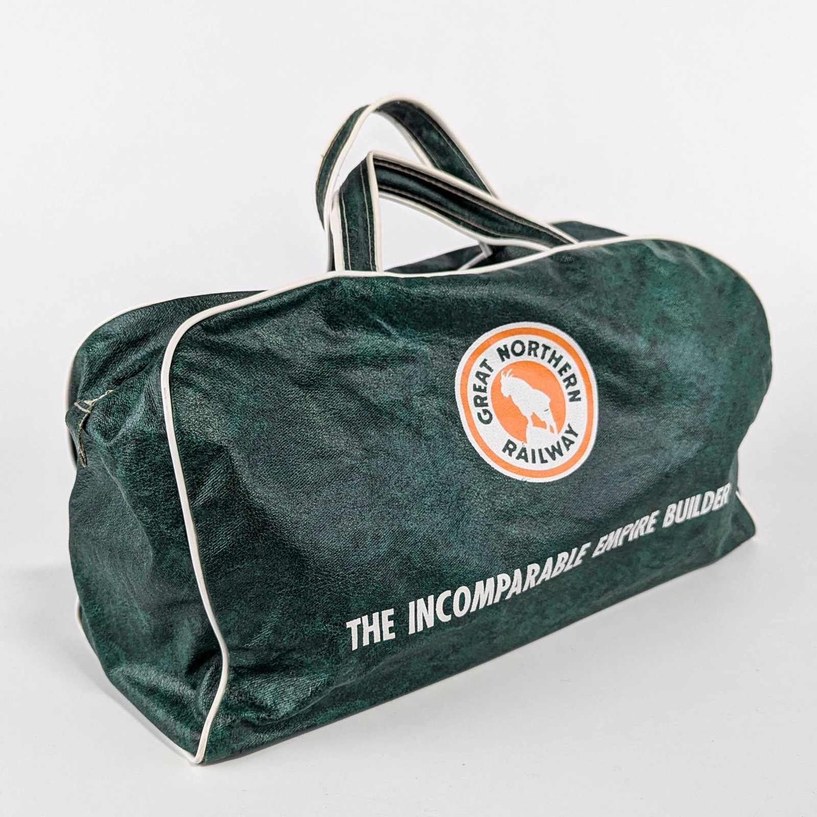 Great Northern Railroad Green Overnight Bag: One Great Northern Railroad green overnight bag. Both sides with an orange and white logo. One side with a leaping Rocky the Goat mascot. The other side with "The Incomparable Empire Builder.&quo