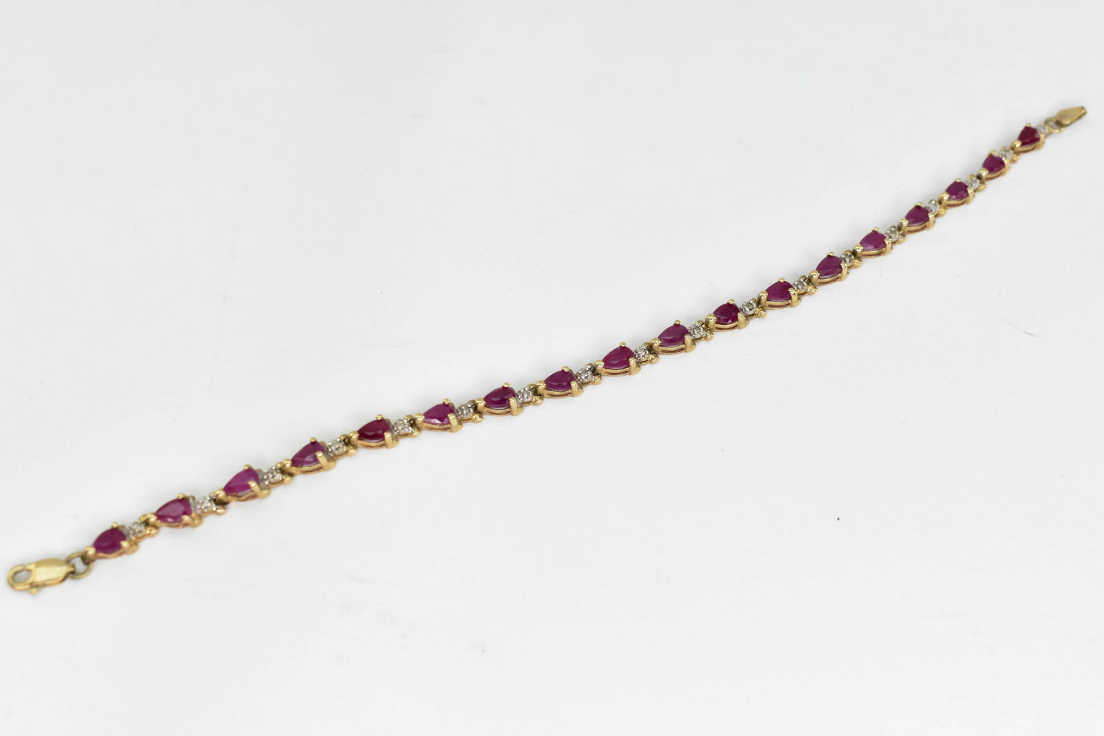 Gold-tone Bracelet: 7"L bracelet set with pink stones and low quality diamonds.