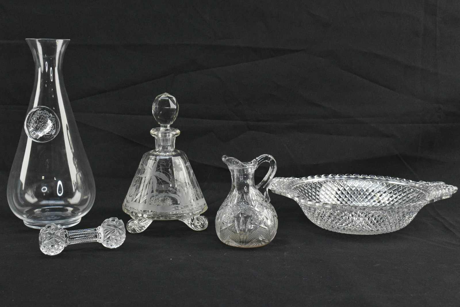 5 Clear Glass Serving and Dinnerware Objects: Group of five clear glass objects. Includes one wine carafe with grape design in relief, one knife rest with cut star designs, one creamer jug with fan and star decoration, one serving bowl with criss