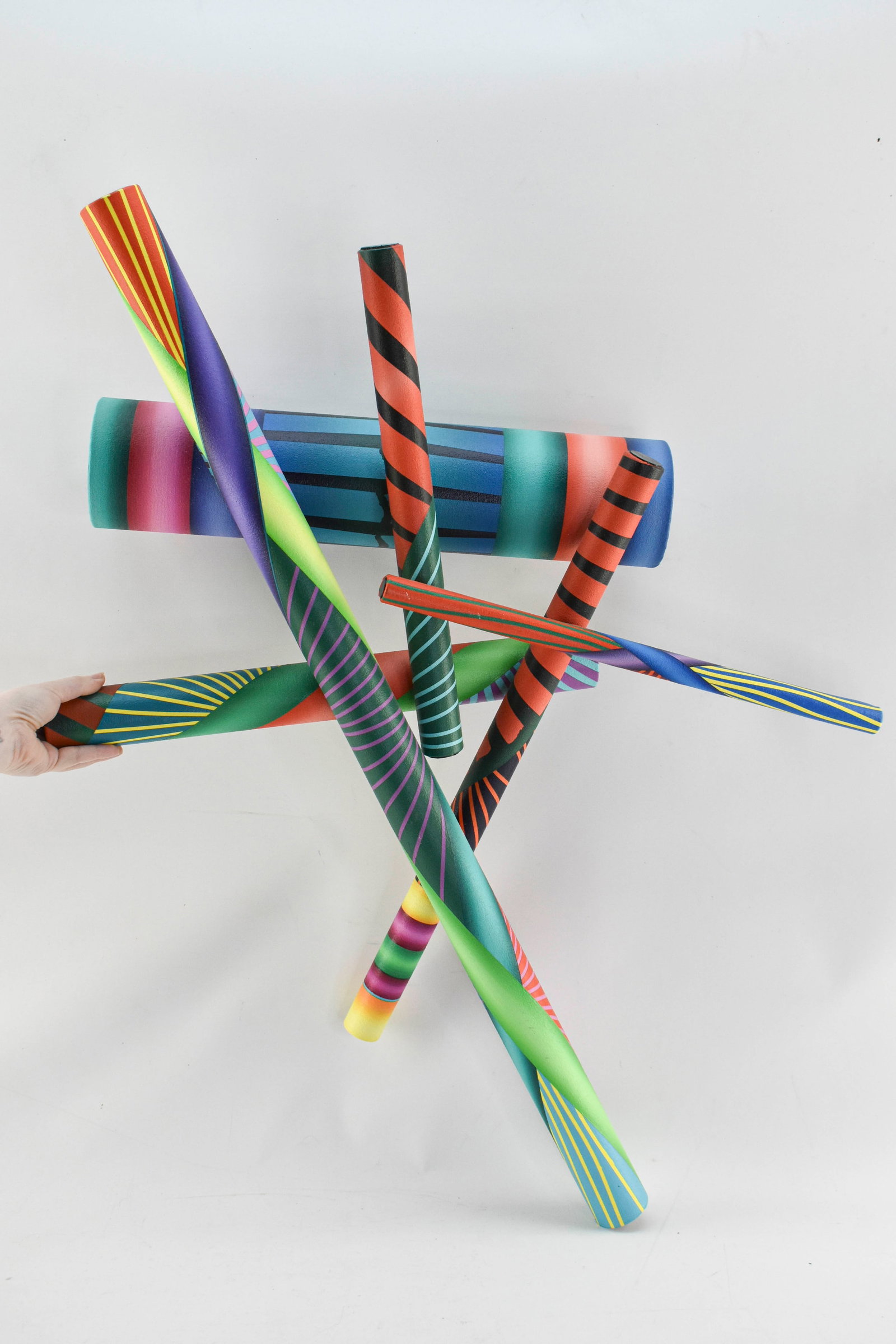George Snyder "Fate Strikes" Sculpture, 1997: Colorful wall-mount sculpture by George Snyder. Appears to be constructed from wooden dowels wrapped in painted canvas and attached with hardware. Includes two metal rings for hanging. 36"H x 28&