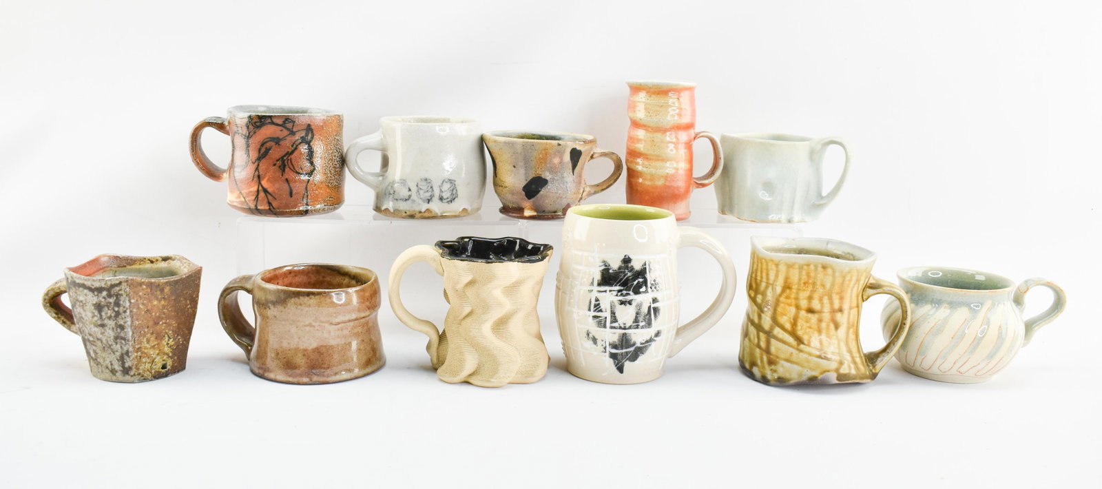 Group of Studio Pottery Mugs: 11 studio pottery mugs by different artists including Linda Lid (Norway) and Bede Clarke (Columbia, Missouri) among many others. Most ugs have maker's marks. Largest mug: 4.75"H x 5"L x 3.25