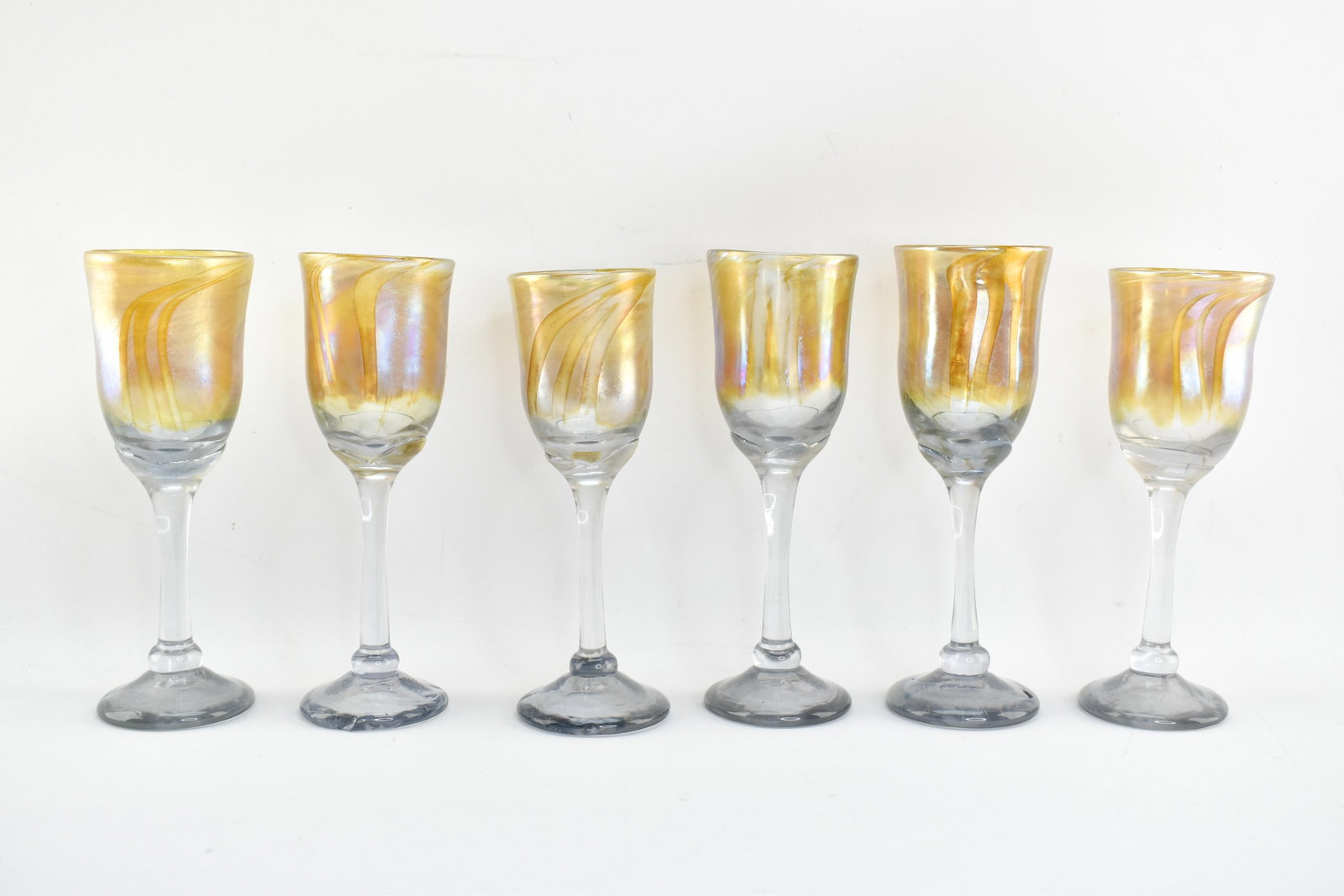 6 Hand-Blown Iridescent Amber Goblets: Set of 6 vintage handmade goblets with irisdescent amber design. Appear to be made of two pieces of glass fused together - stem and bowl. Each glass is illegibly signed on the bottom. There is minor v