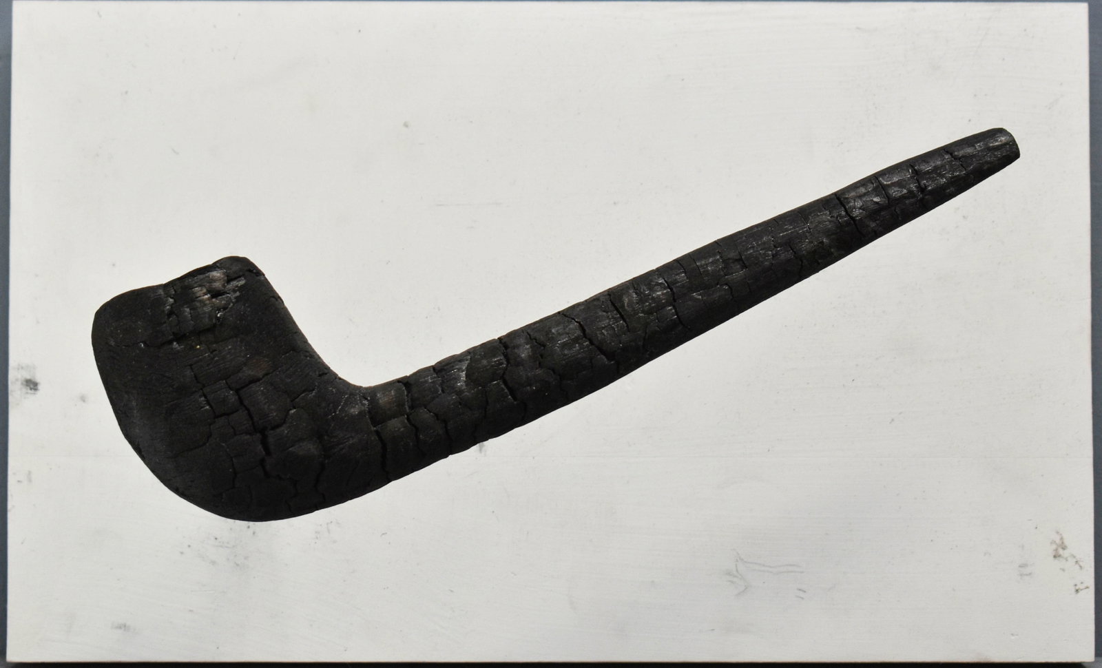Andy Yoder "Late One Morning" Sculpture: Sculpture made from a charred piece of wood in the shape of a smoking pipe. MAde in 2007 from burnt walnut wood and Azek board. Signed on verso. 8"H x 13"W x 6.5"D.