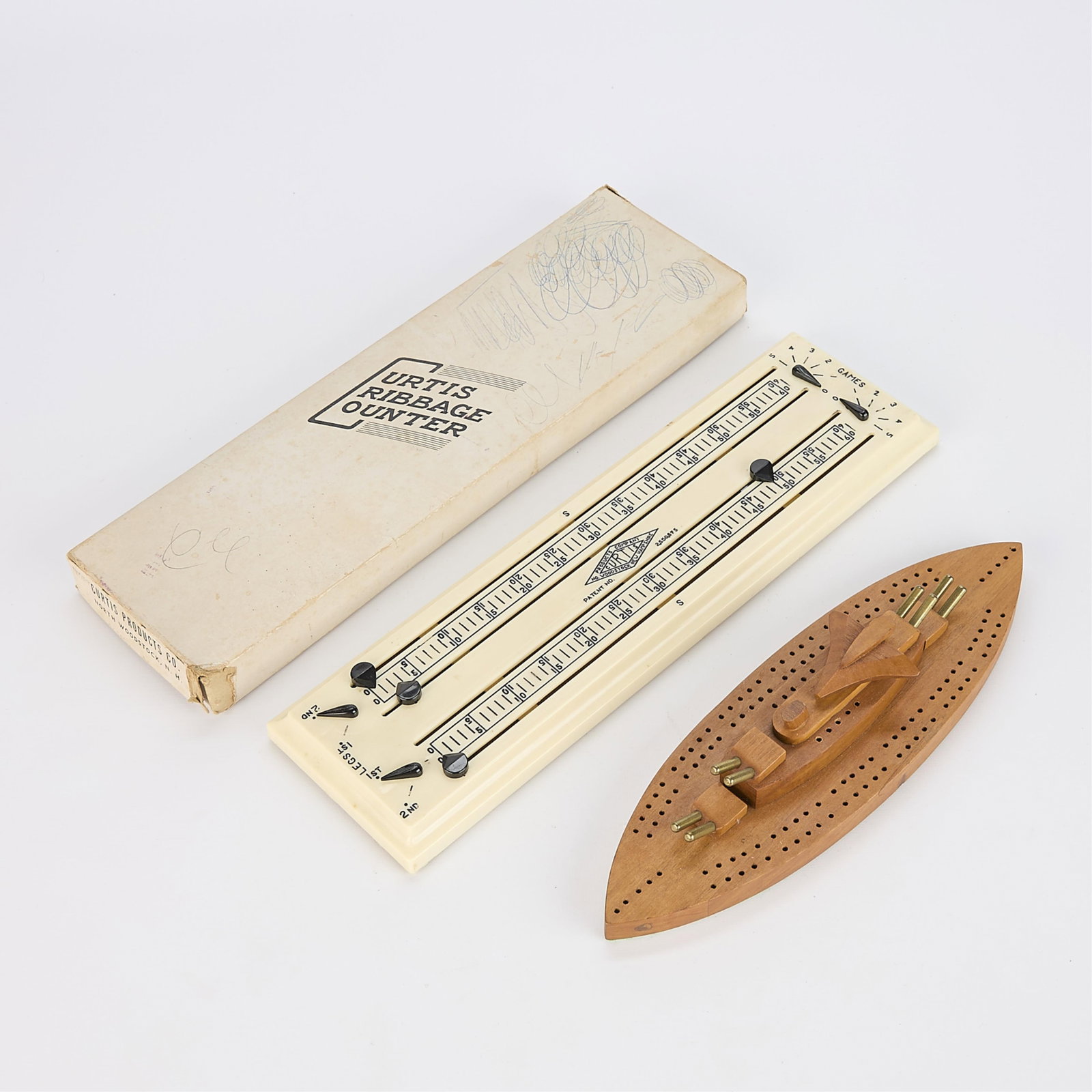 2 Vintage Cribbage Boards - Curtis Counter & Gunner Ship: Group of two antique wooden cribbage boards including: A Curtis Cribbage Counter with the original box. A hand-carved wooden cribbage board in the form of a WWII gunner ship complete with brass cannon