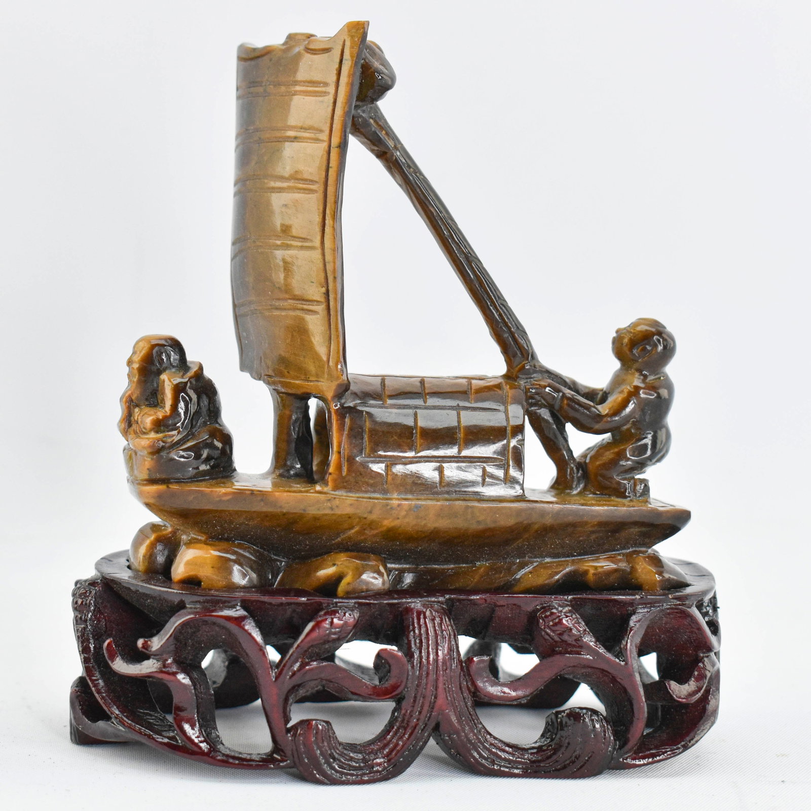 Chinese Tiger's Eye Carving of Boat: Tiger's eye carving in the form of two figures on a small boat. Firmly attached to custom wood base. 4.75"H x 4.25"W x 2.25"D