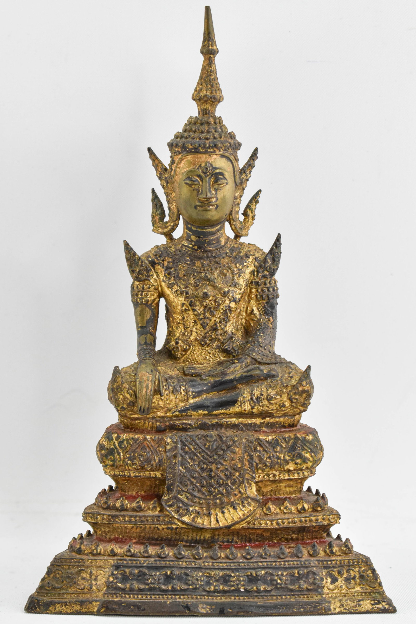 Gilt Metal Thai Buddha Statue: Gilt metal statue depicting Buddha. Areas of red paint and mounting rings indicate possible use as an ornamental architectural element. 8"H x 5"W x 3"D.