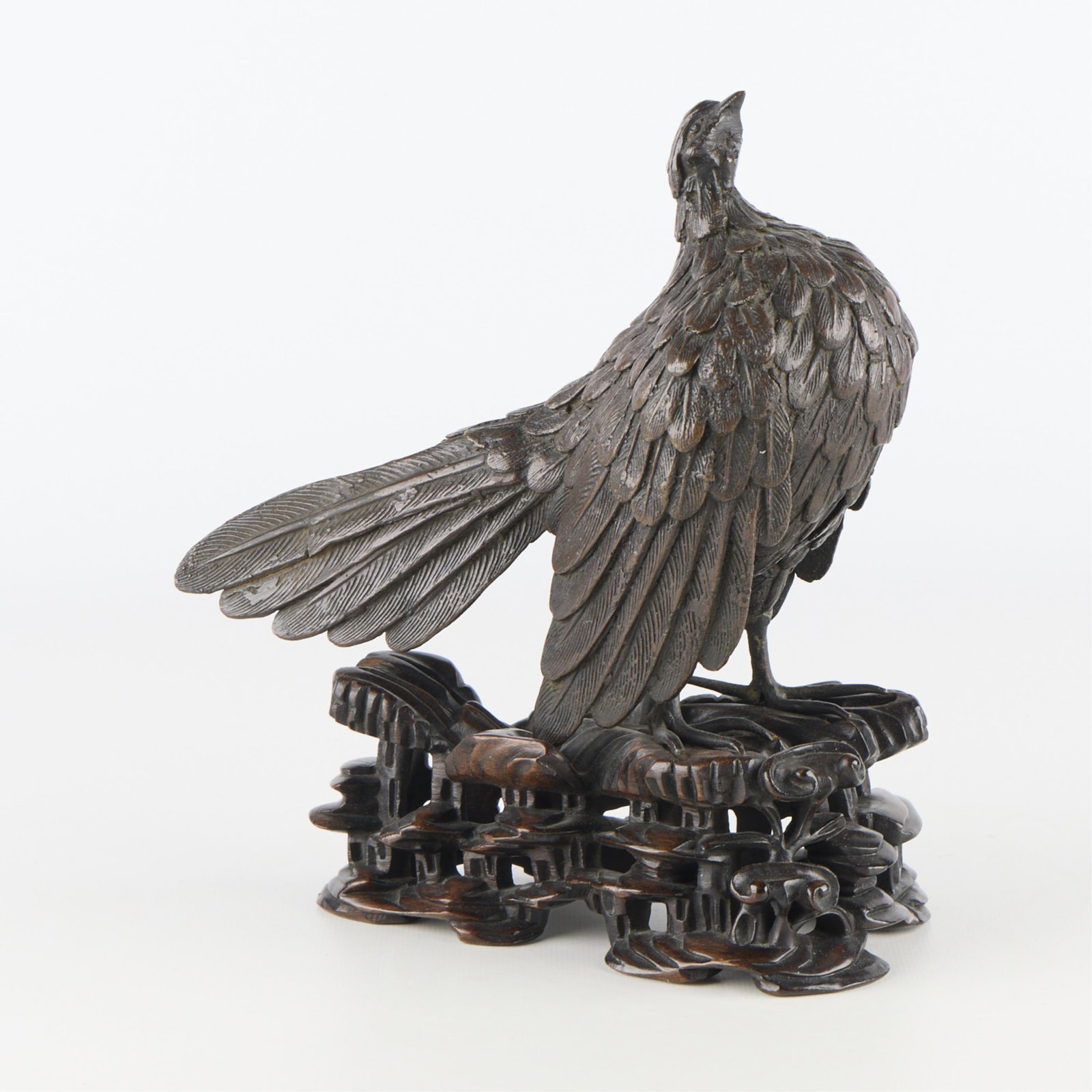 Asian Bronze Bird w/ Carved Stand: Patinated bronze bird on a carved wooden stand, possibly Japanese or Chinese. Height: 8 1/2 in x width: 4 1/4 in x depth: 8 in.
