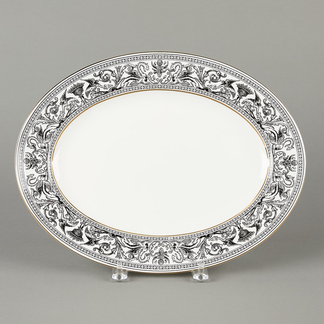 Wedgwood Florentine Porcelain Oval Platter: Porcelain Wedgwood oval platter in pattern "Florentine." Decorated with detailed black and white mythical motifs and gilt rim. 15 1/2"L x 11 3/4"W.