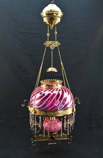 Antique Victorian Parlor Lamp with Pink & White Swirl Glass: Antique Victorian hanging parlor oil lamp. Features a cranberry red or pink glass shade, font, and chimney with swirling stripes of white throughout. Metal structure has scrolled, pressed, and etched