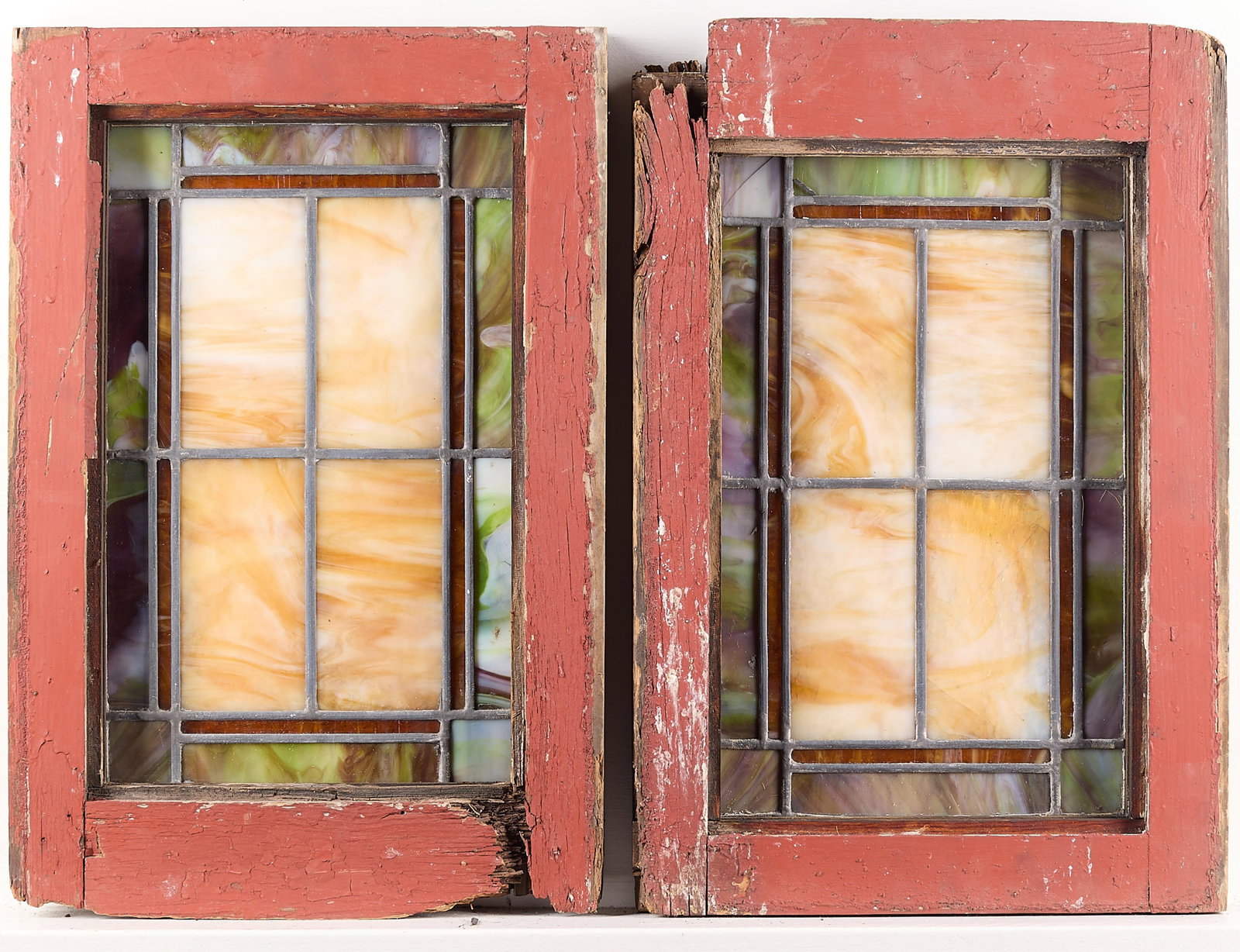 Set 2 Arts & Crafts Stained Glass Windows: Pair of Arts & Crafts slag stained glass windows. Squares and rectangles of yellow, purple-green, and orange. In painted red wood frames.Each, height: 21 3/4 in x width: 14 1/2 in x depth: 1 3/4 in.