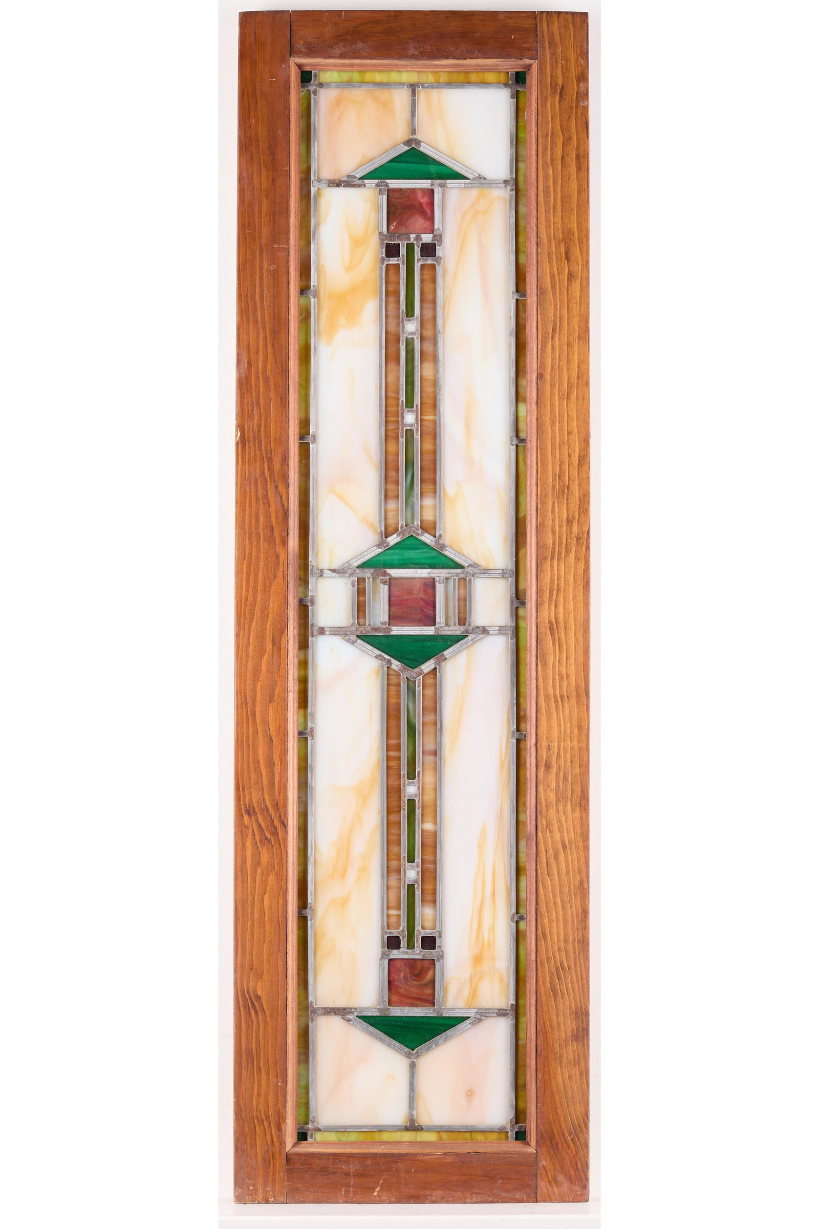 Arts & Crafts Stained Glass Window Arrow: Arts & Crafts slag stained glass window with a double arrow motif. In cream, orange, red, and green.Height: 12 1/2 in x width: 43 in x depth: 1 in.