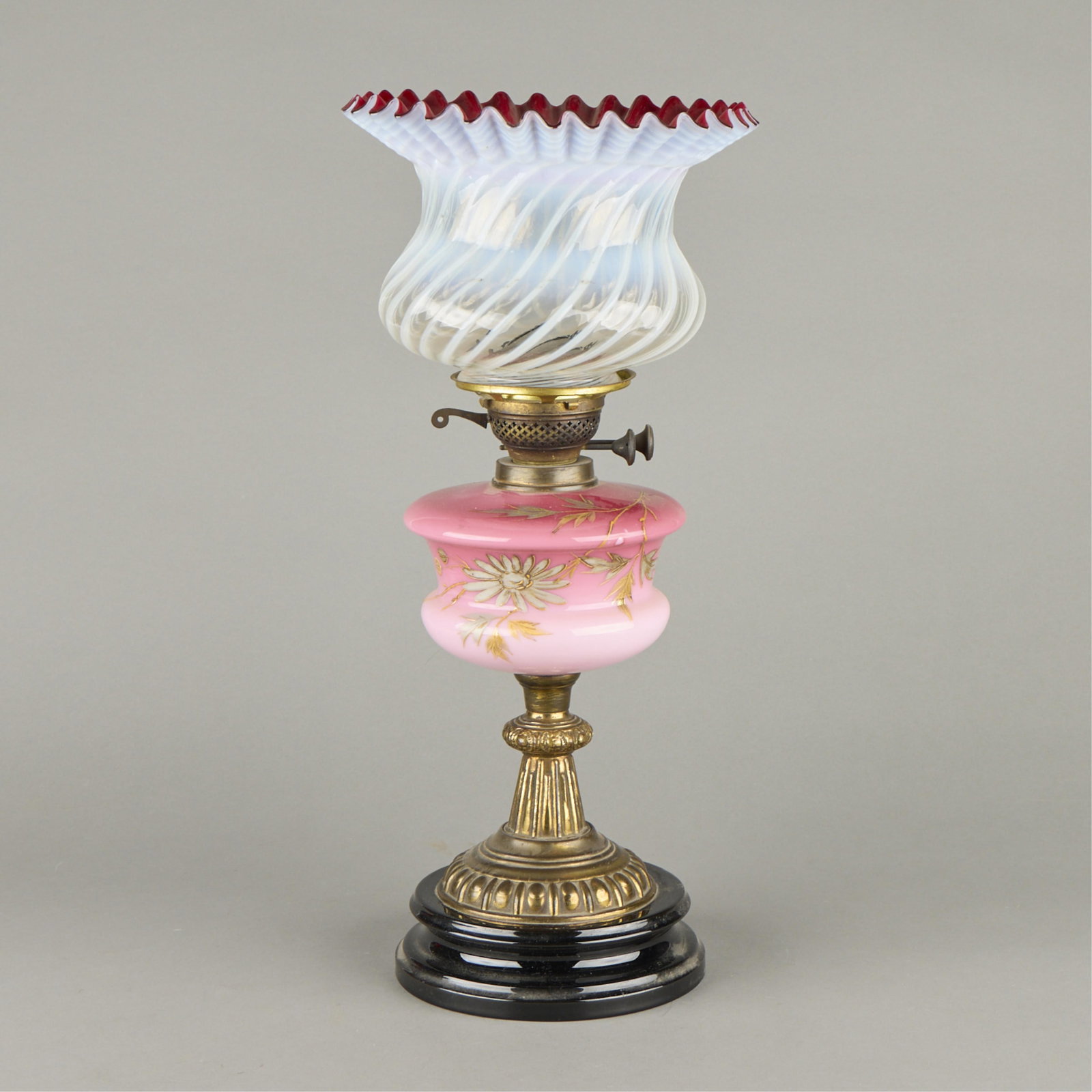 Painted Cranberry Glass Floral Table Lamp: Antique cranberry glass oil lamp or banquet lamp. With painted leaves along the side. Ruffled edge to the glass dome.Height: 21 1/4 in x diameter: 10 in.