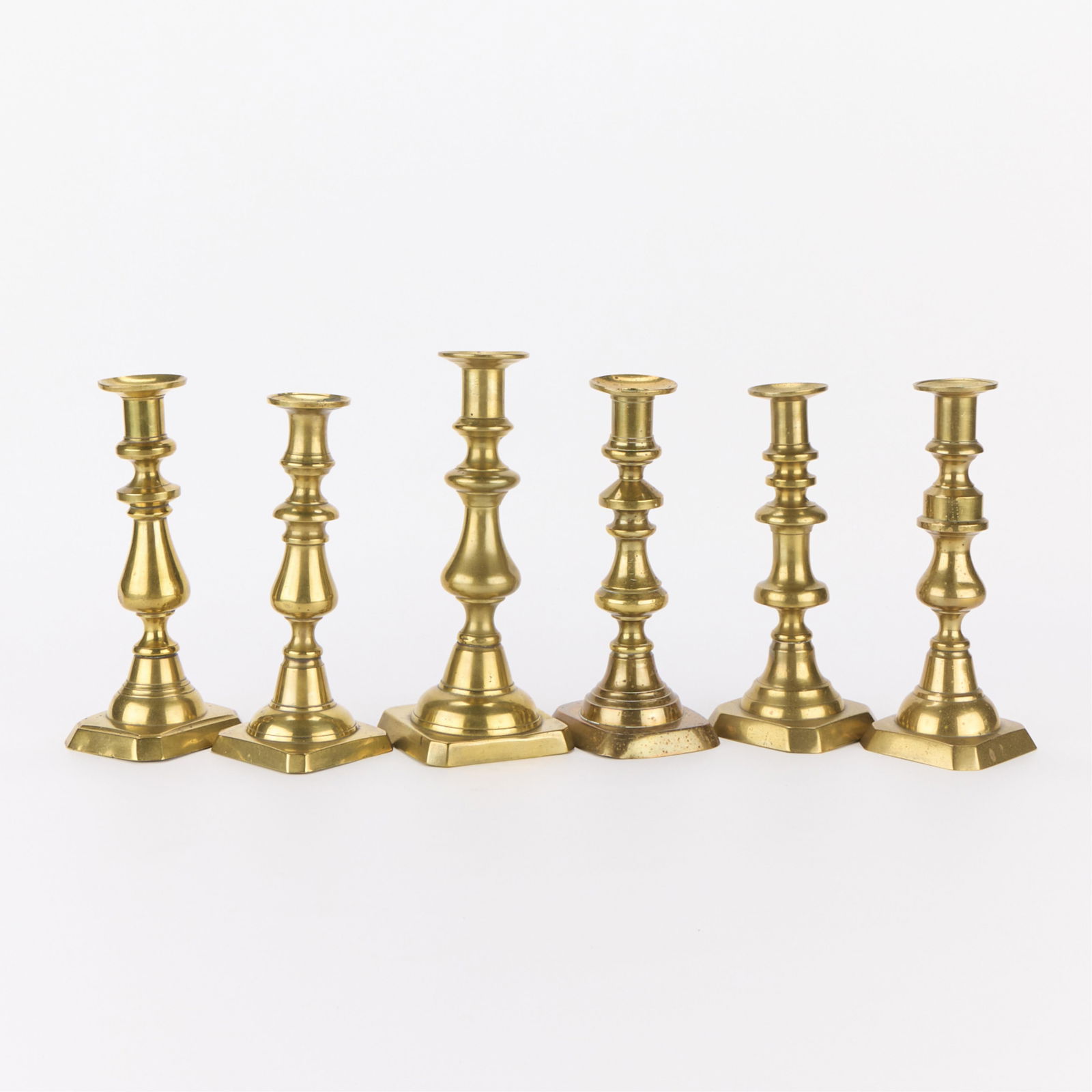 6 Vintage Brass Push-Up Candlesticks: Group of six vintage brass candlesticks. Not matching.Height ranges from 8 1/2 in to 9 1/2 in; diameter ranges from 3 1/4 in to 4 in. Gross weight: 4 lbs 14 oz.