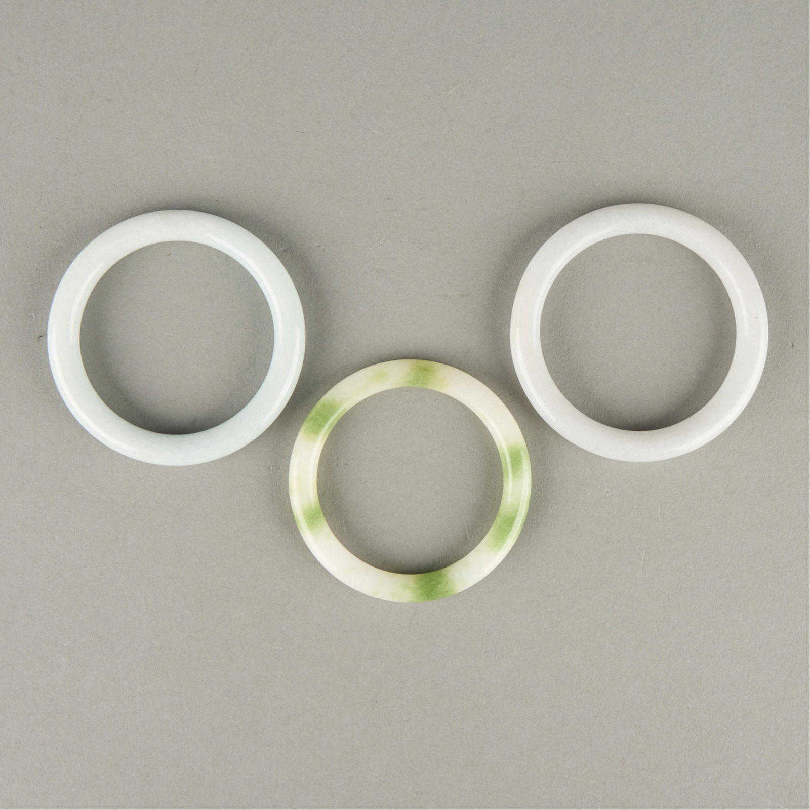 3 Chinese Jade Bangles: Group of three Chinese jade bangles.Inner diameter ranges from 2 1/4 in to 2 1/2 in; outer diameter ranges from 3 in to 3 1/4 in. Gross weight: 118.4 g.