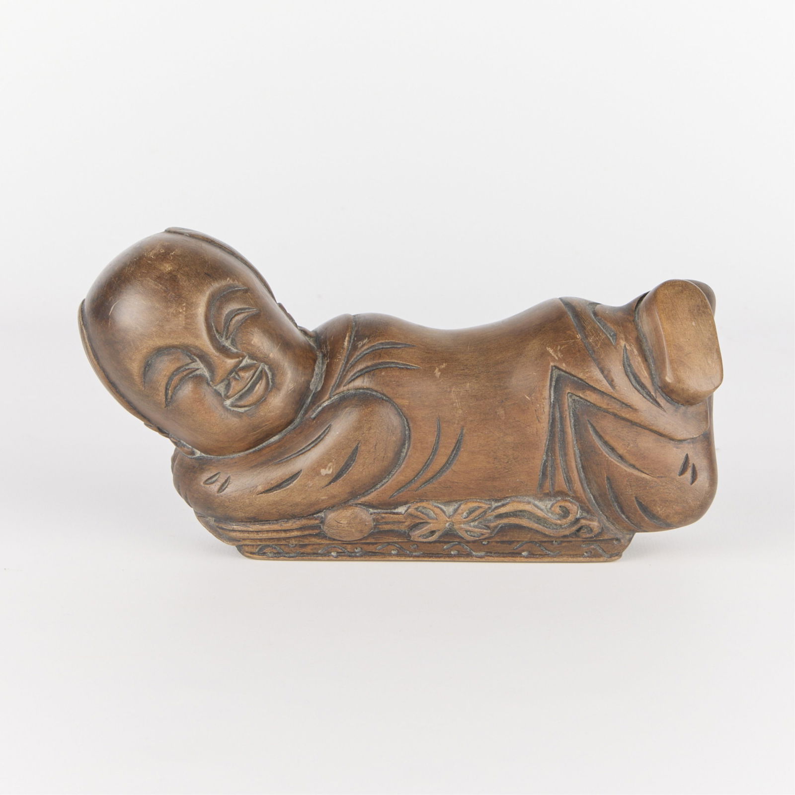 Chinese Carved Wooden Buddha Pillow: Chinese carved wooden pillow in the form of a recumbent smiling buddha.Height: 4 in x width: 8 in x depth: 2 1/2 in.