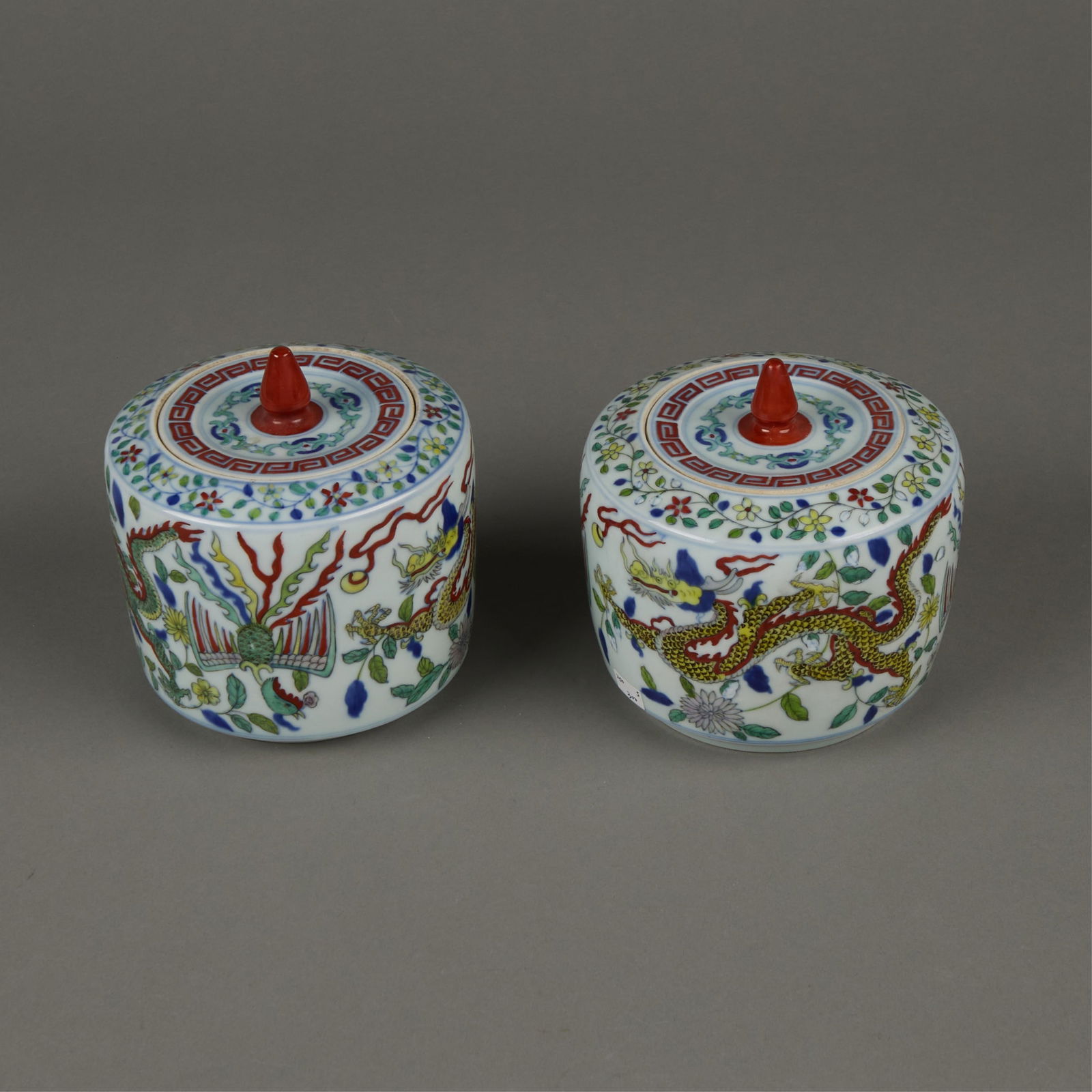 Pr Chinese Wucai Porcelain Lidded Vessels: Pair of Chinese wucai porcelain lidded vessels. Depicting dynamic dragons chasing flaming pearls. Each with a central red finial along the lid.(Each) height: 5 1/2 in x diameter: 5 in.